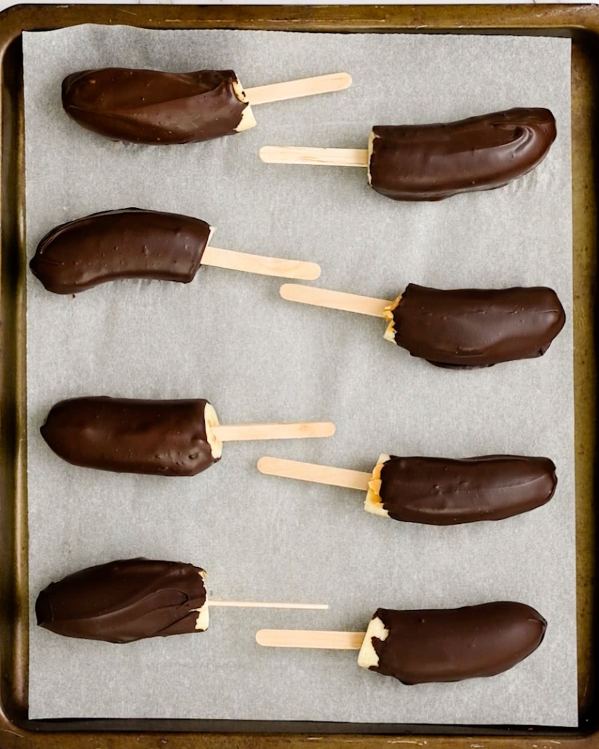 8 Chocolate Peanut Butter Frozen Bananas on a baking sheet to freeze 