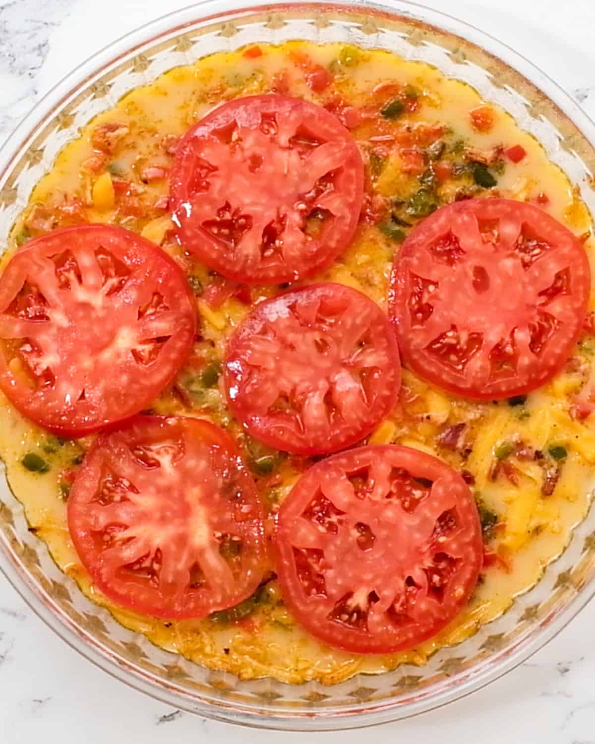 Hash Brown Crust Quiche topped with tomato slices before baking