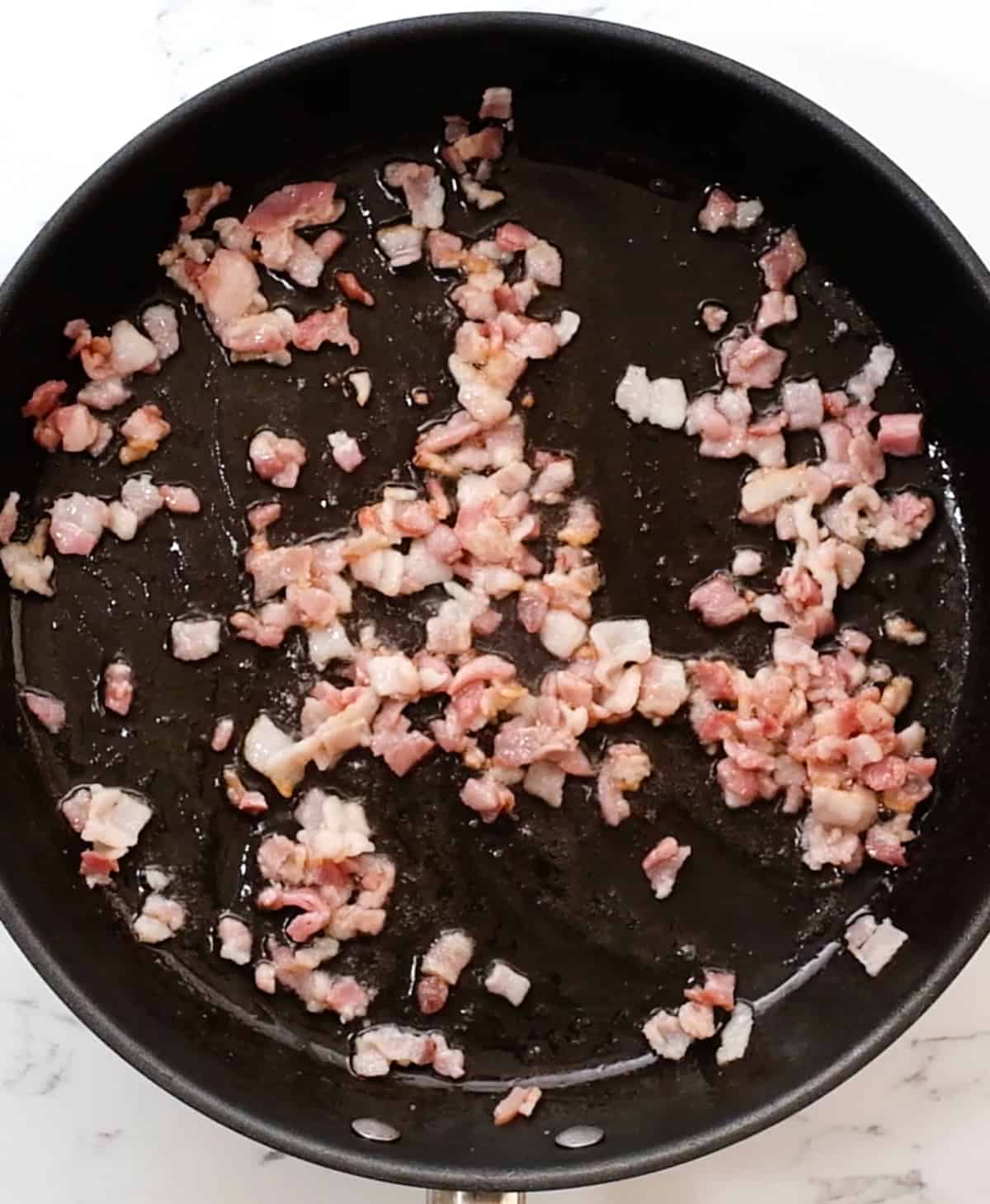 bacon in a fry pan after partially cooking