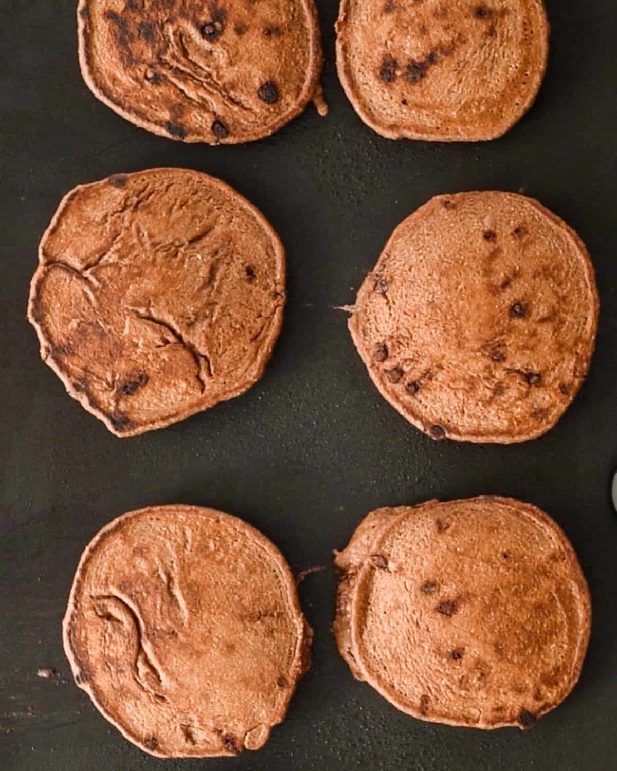 Healthy Chocolate Pancakes cooking on the second side on a griddle