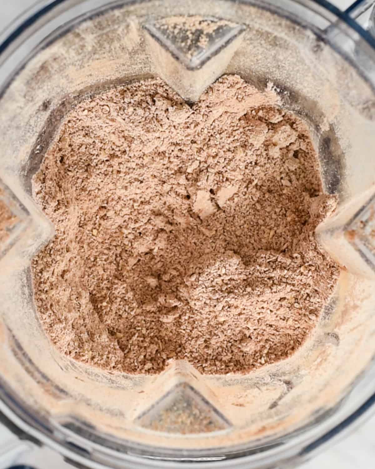 oats and cocoa powder in the container of a blender after blending to make Healthy Chocolate Pancakes 
