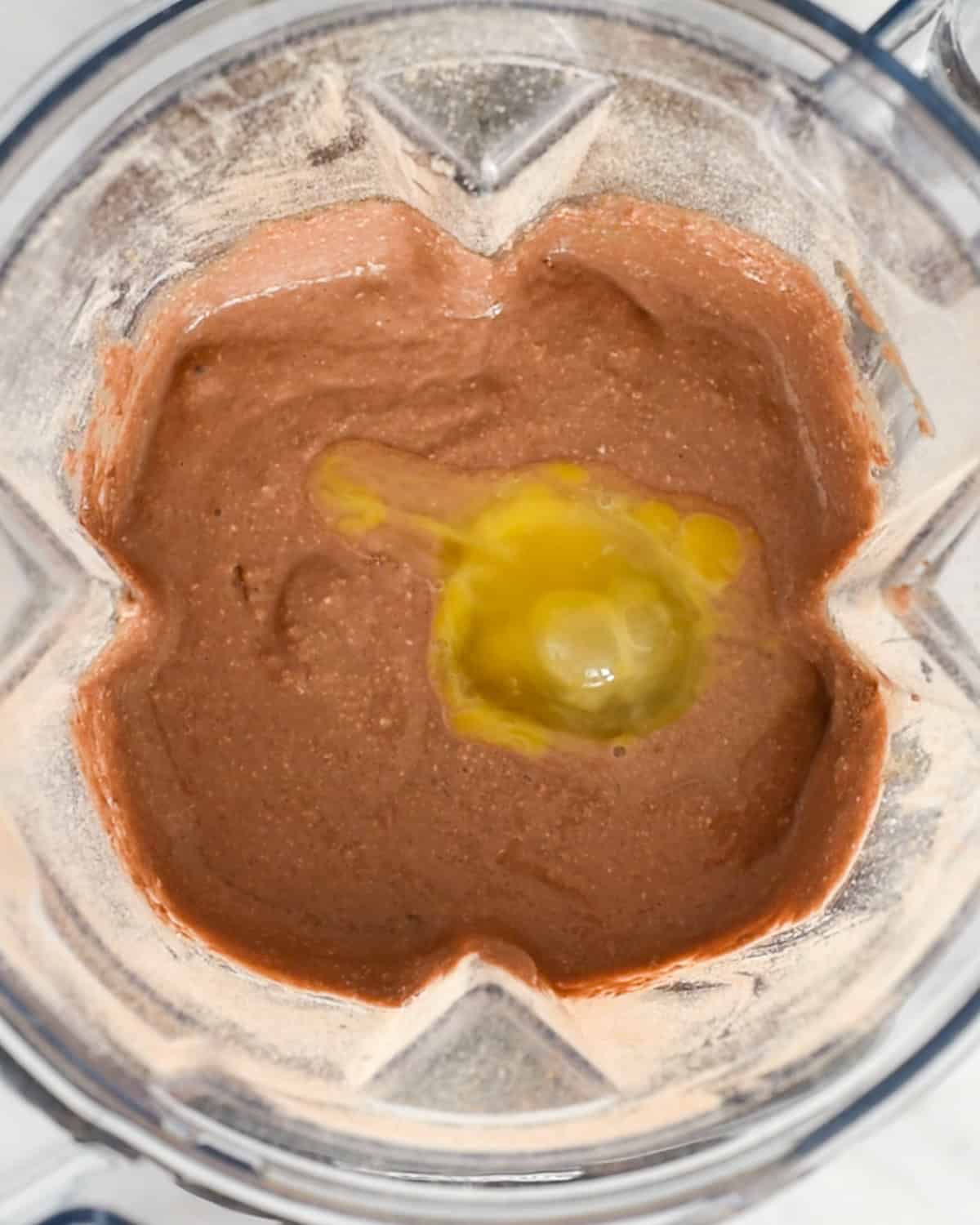 egg added to the batter of Healthy Chocolate Pancakes in a blending container
