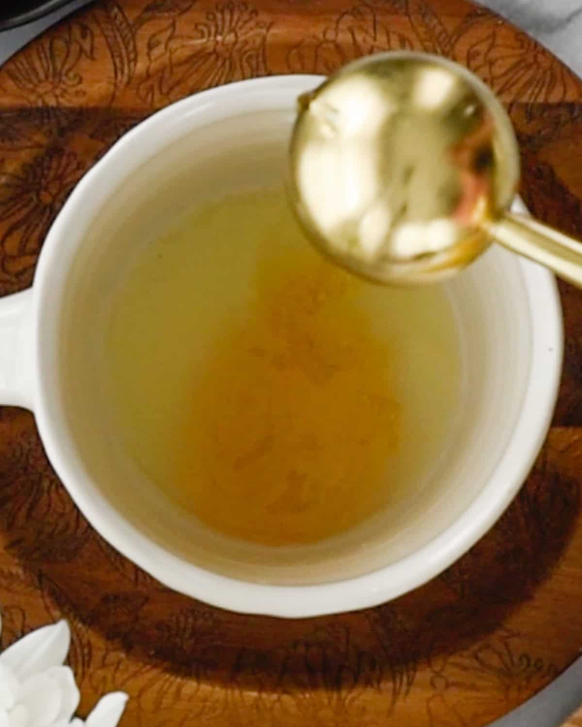 How to Make Immune Boosting Tea pouring honey into a mug with lemon juice