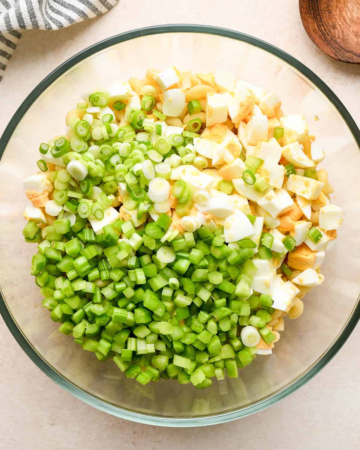 How to Make Macaroni Salad - adding eggs, onion and celery to the cooked macaroni in a bowl