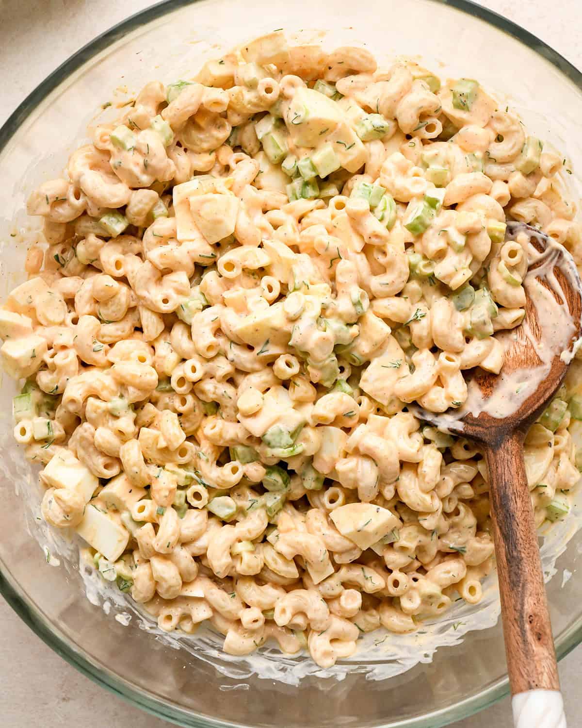 macaroni salad mixed in a bowl with a wooden spoon