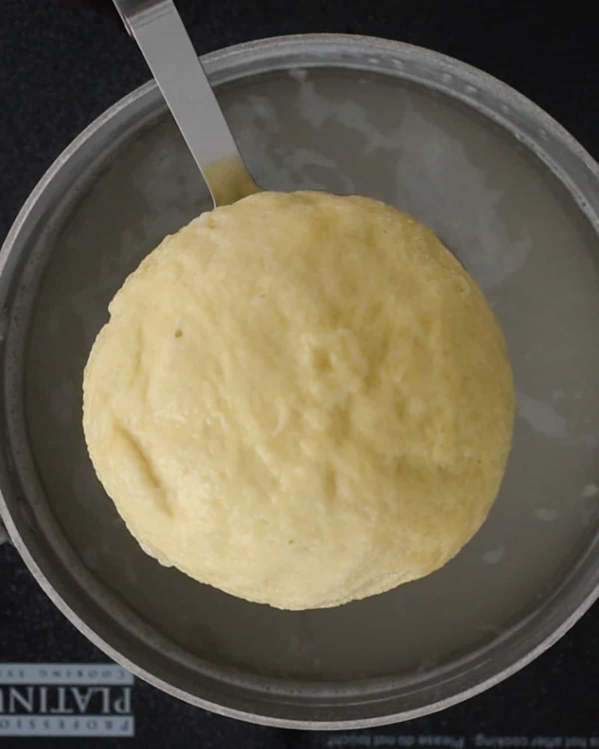 How to Make Pretzel Bread  - dough being removed from a baking soda water bath