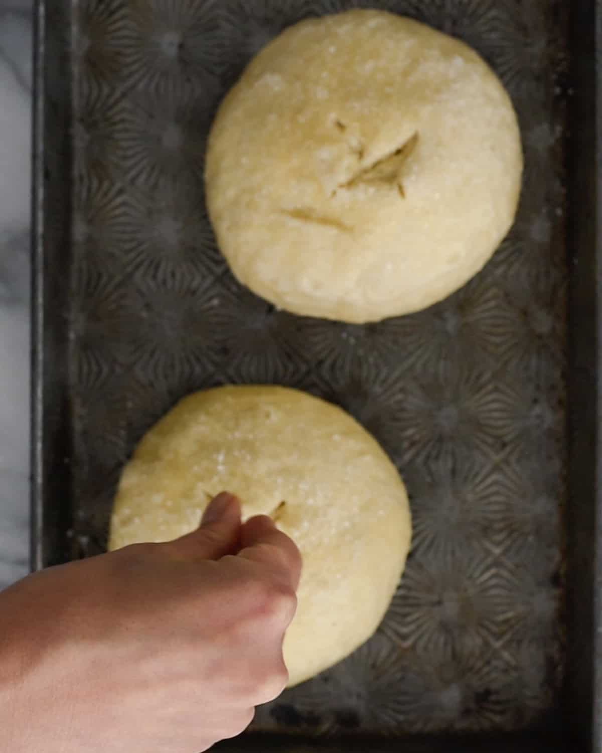 How to Make Pretzel Bread - sprinkling salt over loaves before baking