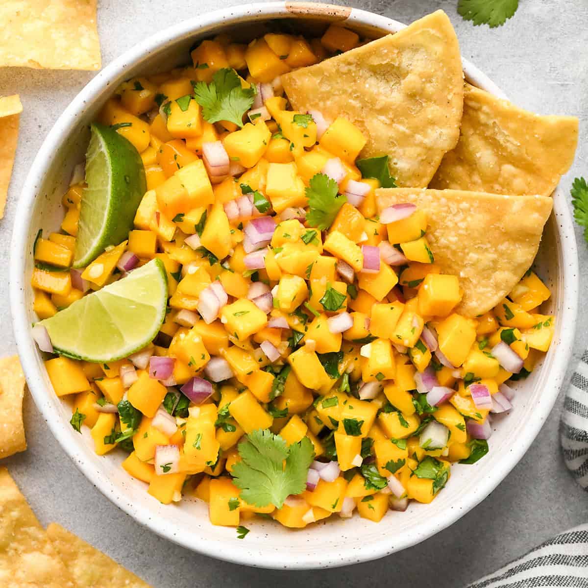 a bowl of Mango Salsa with 3 chips in it