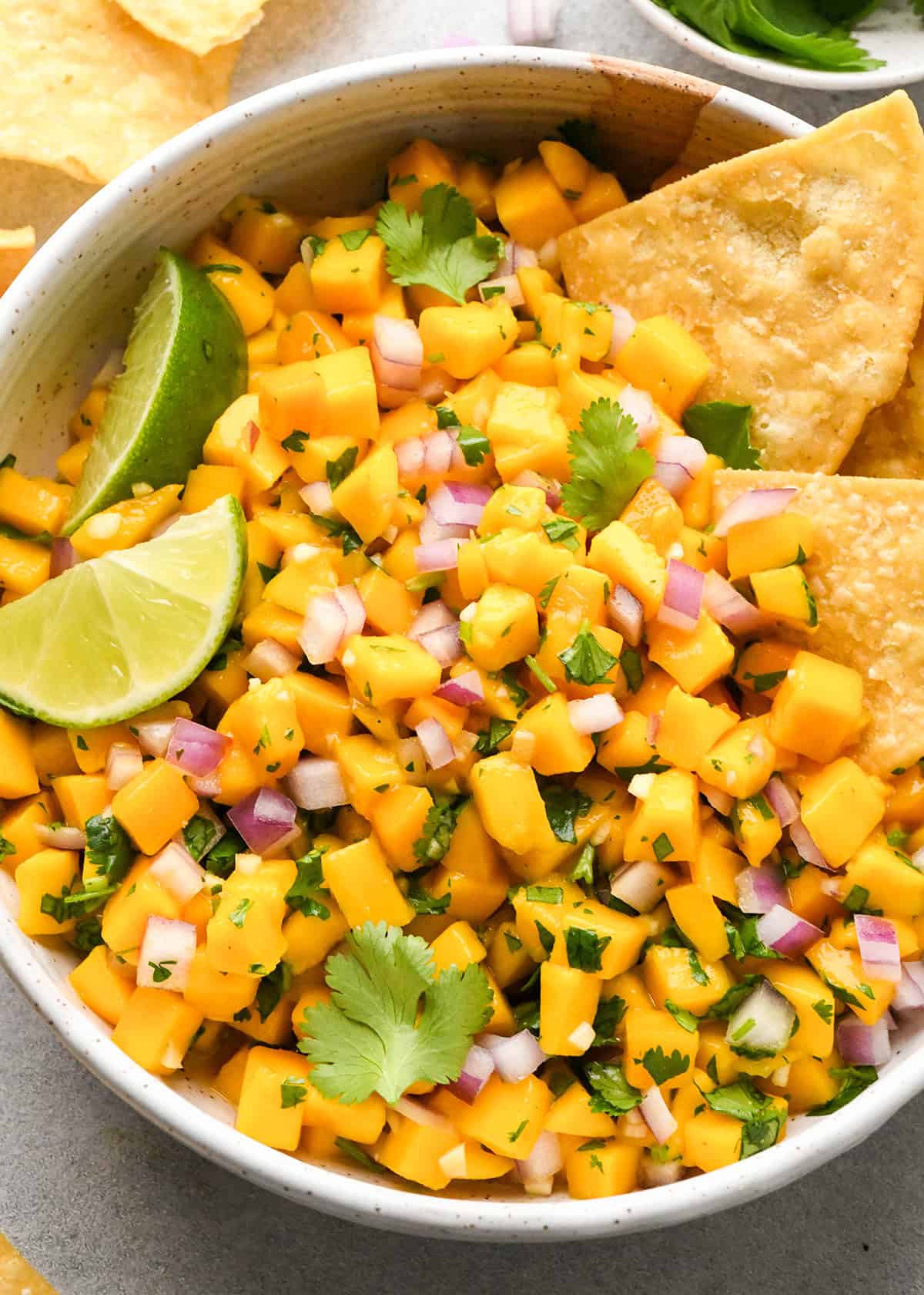 Mango Salsa in a bowl with chips, cilantro and lime