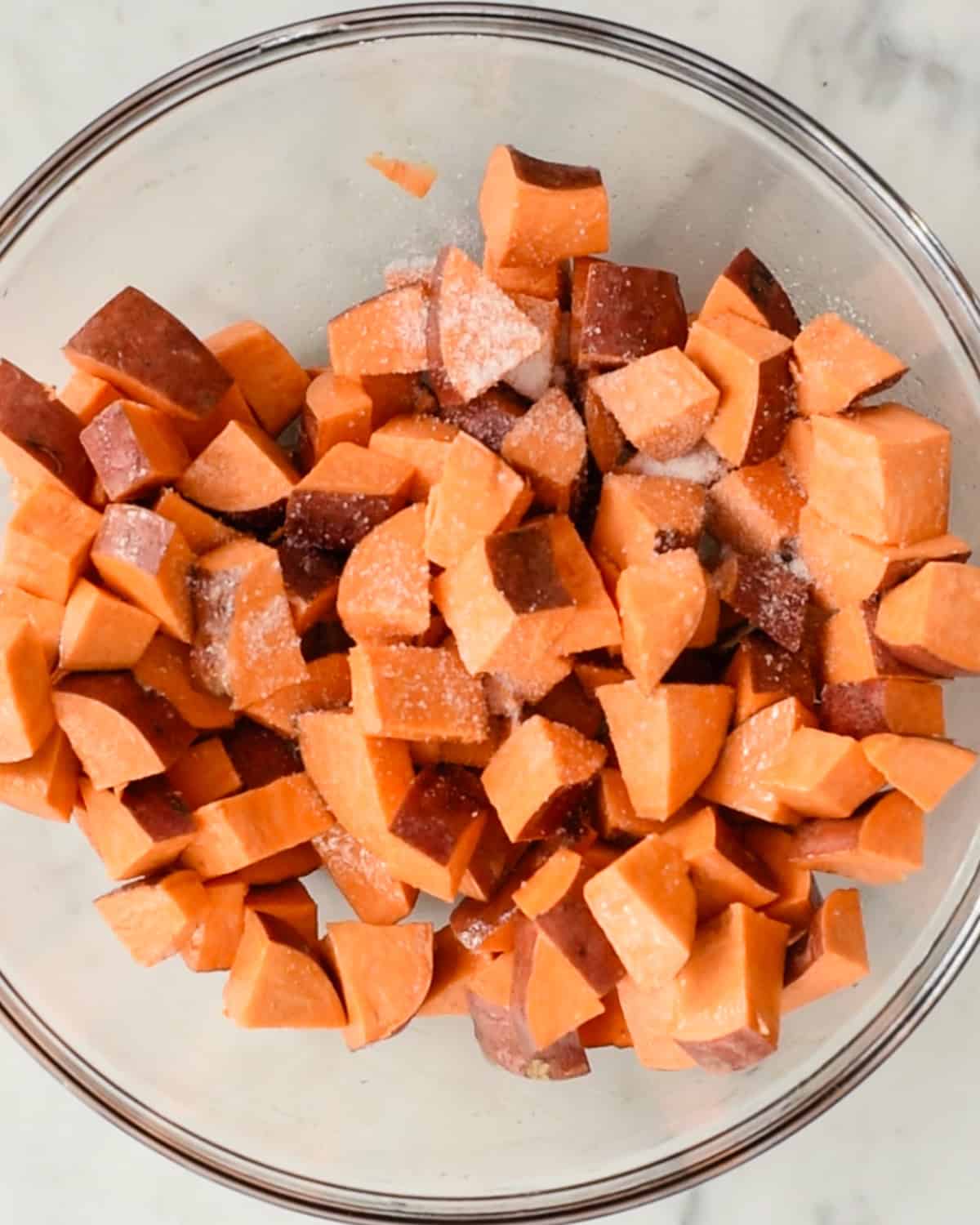 how to make Cinnamon Roasted Sweet Potatoes - adding salt to sweet potato cubes in a bowl