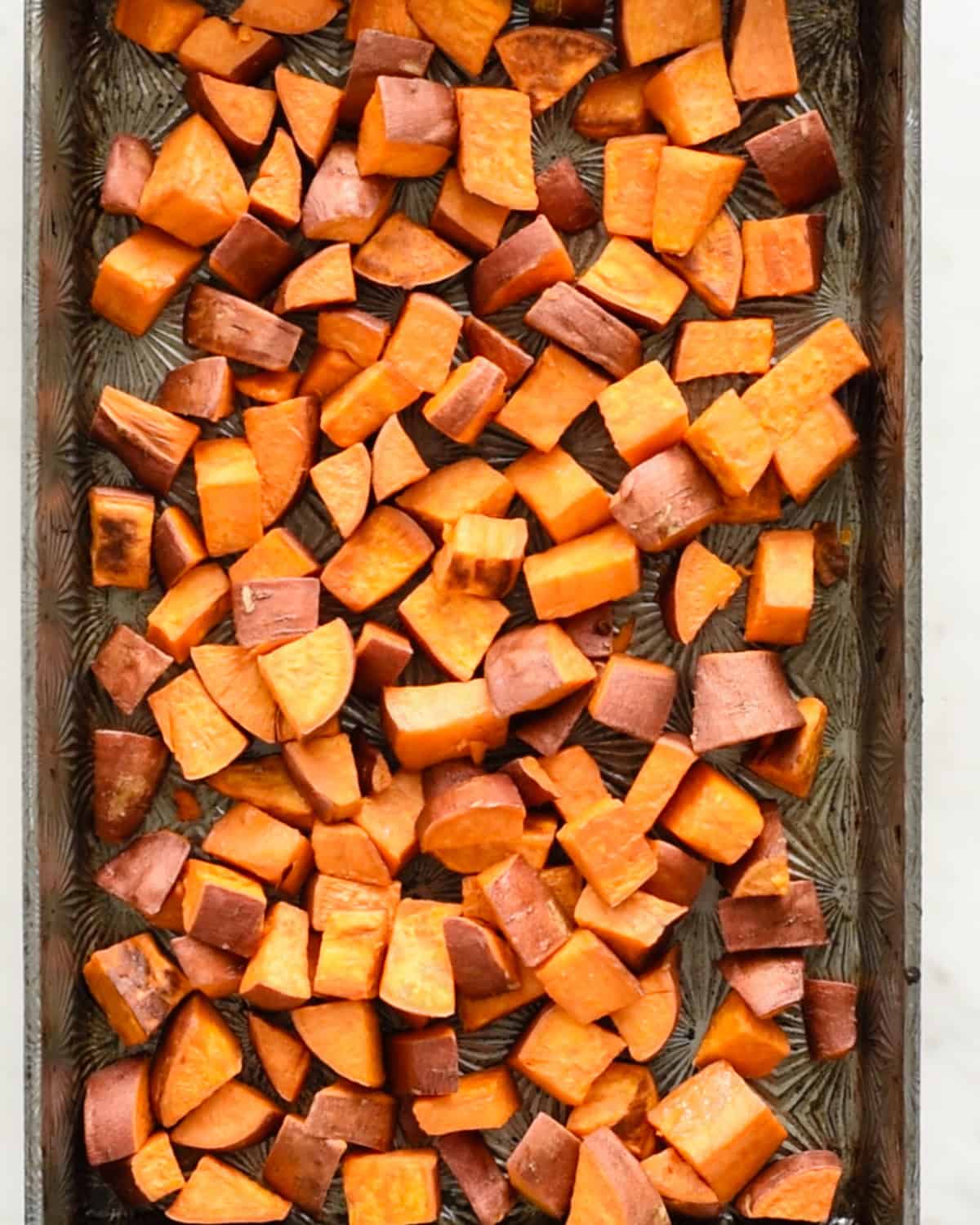 how to make Cinnamon Roasted Sweet Potatoes - sweet potatoes on a baking sheet after partially roasting