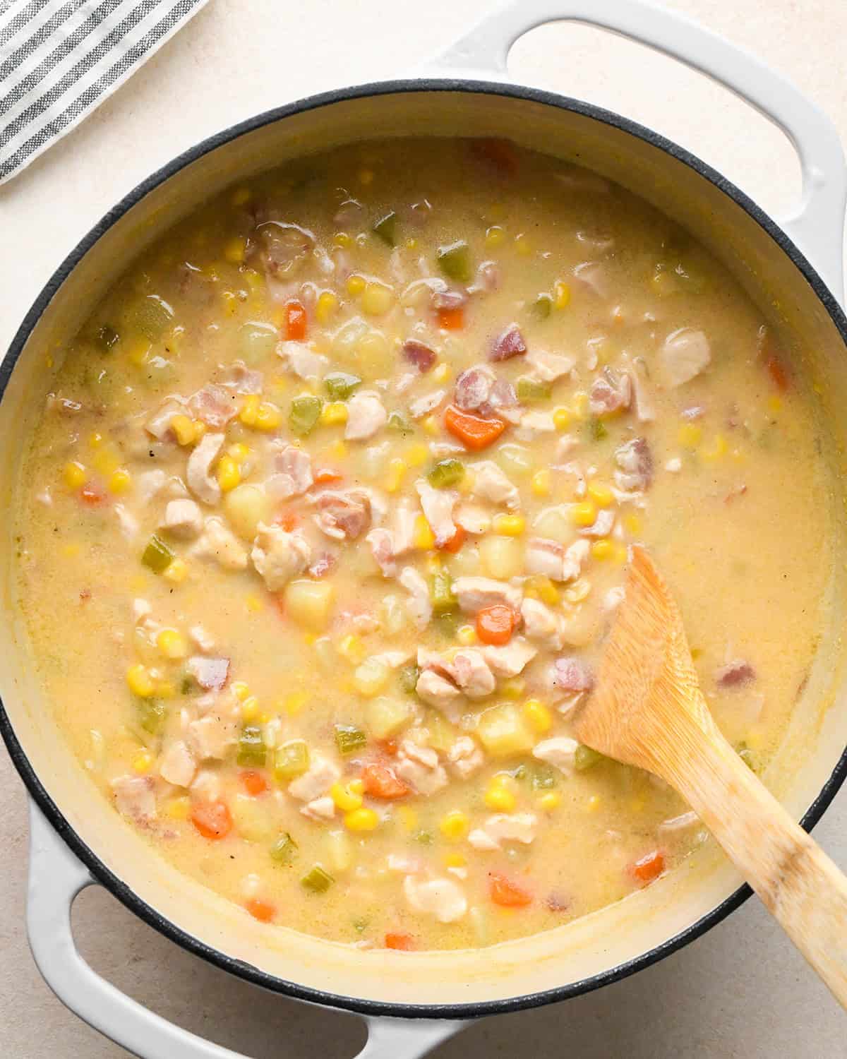 Sweet Corn & Chicken Soup in a pot after the broth has thickened with a wooden spoon