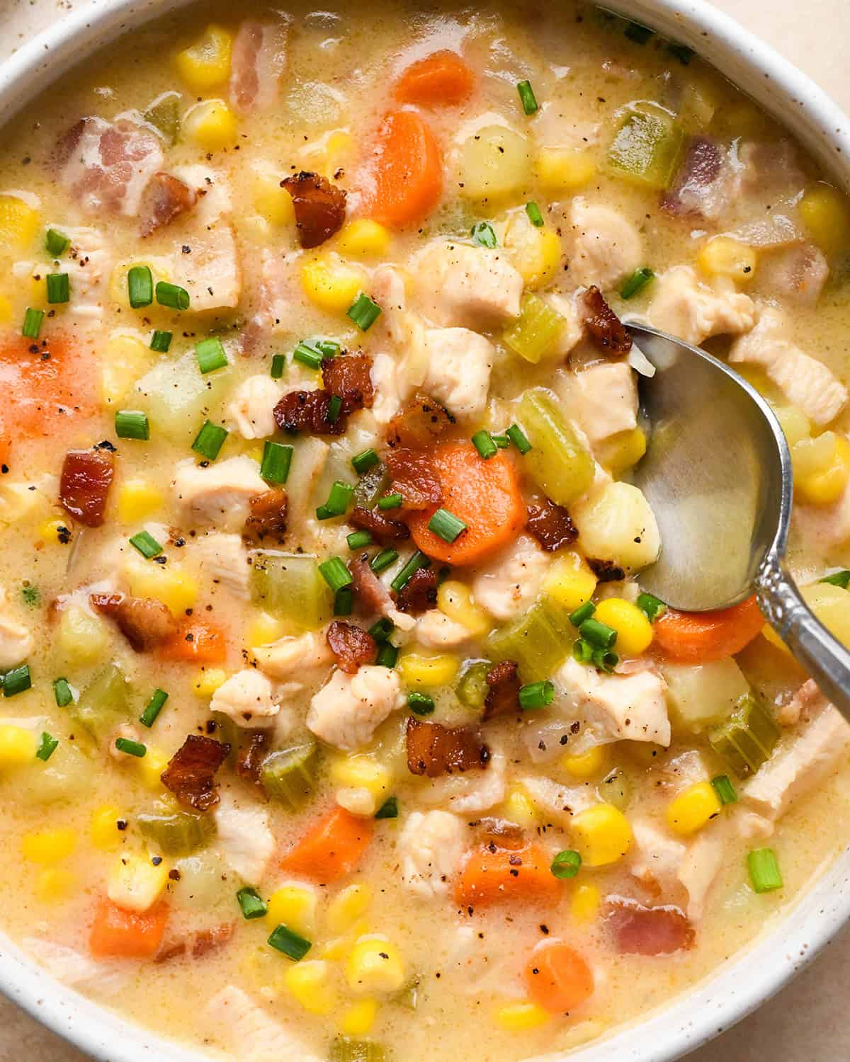 up close photo of a spoon taking a scoop of Sweet Corn & Chicken Soup in a bowl