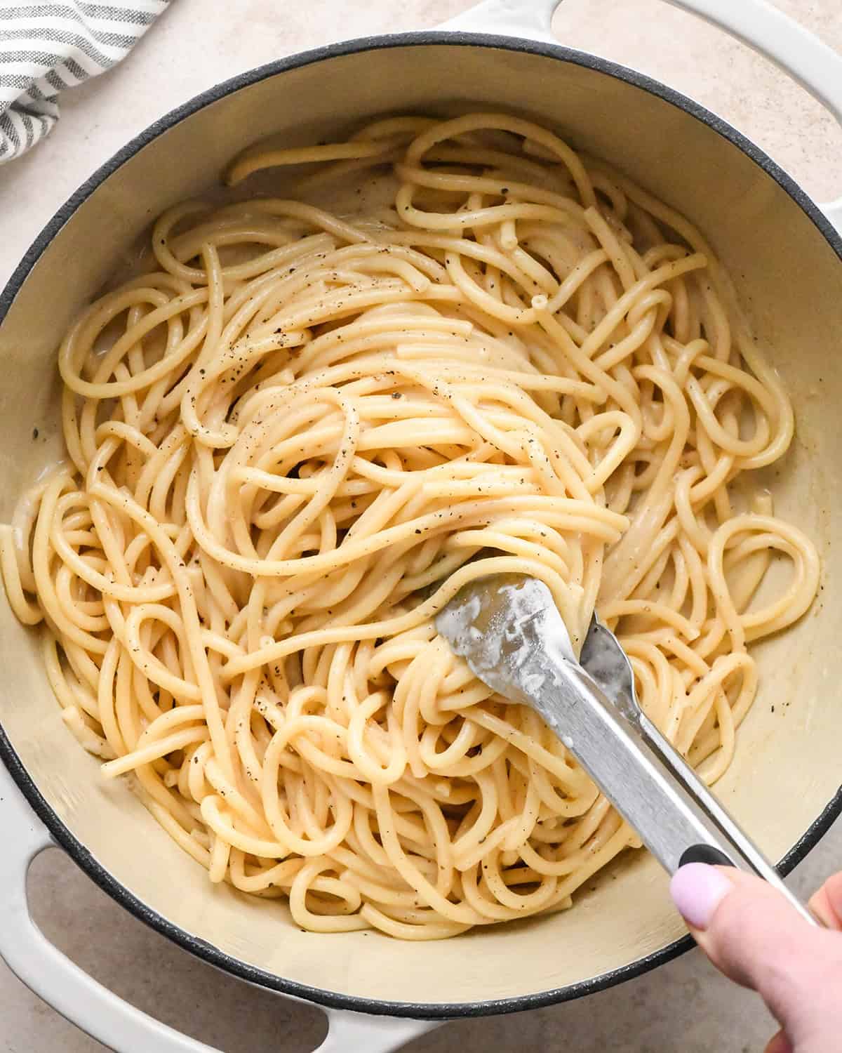 tongs stirring Cacio e Pepe Pasta in a pot