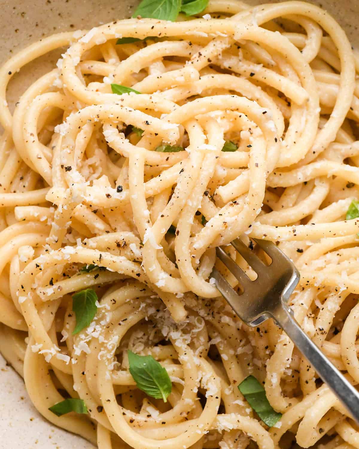 a fork taking a bite of Cacio e Pepe Pasta in a bowl