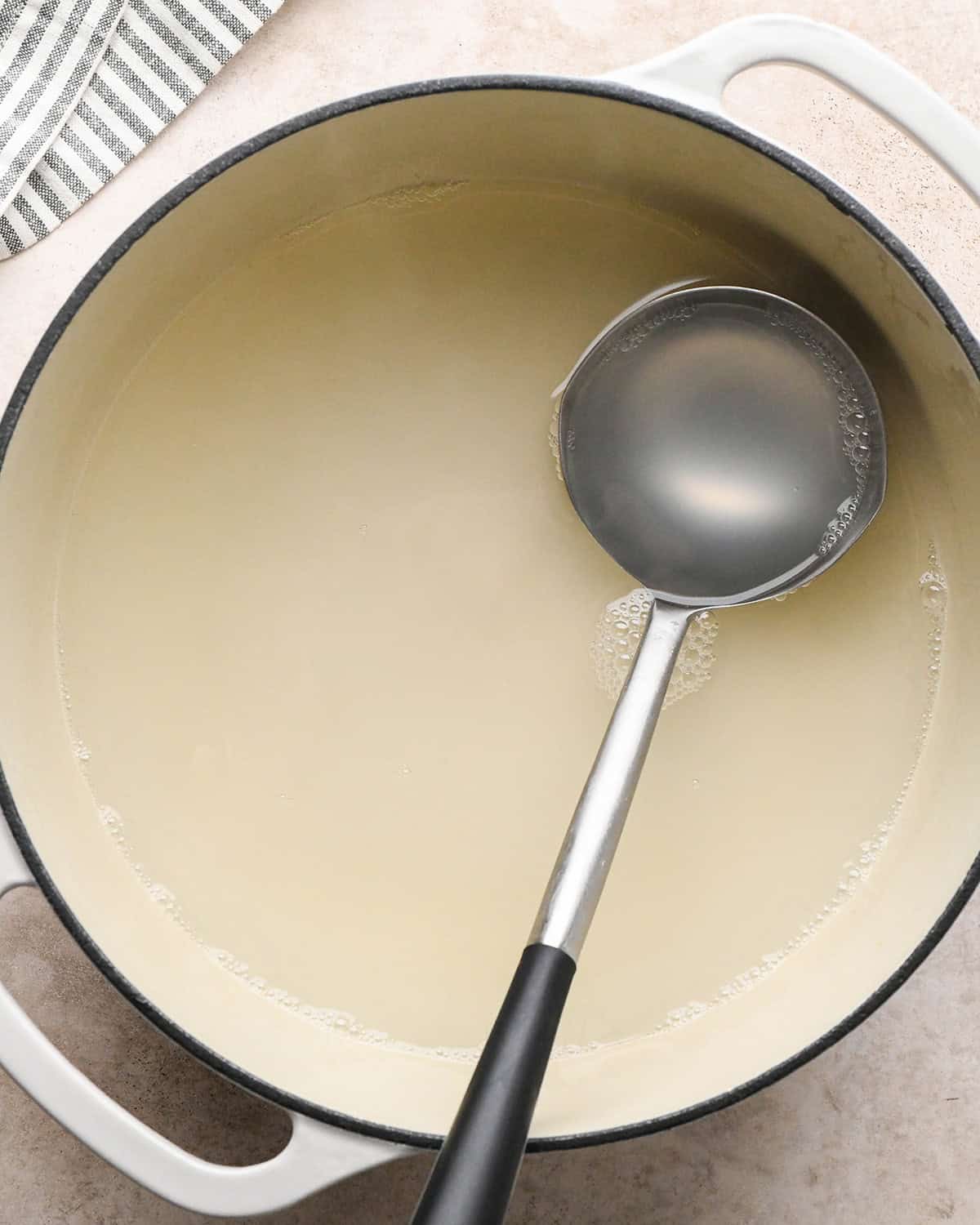 reserved pasta water in a pot with a ladle 