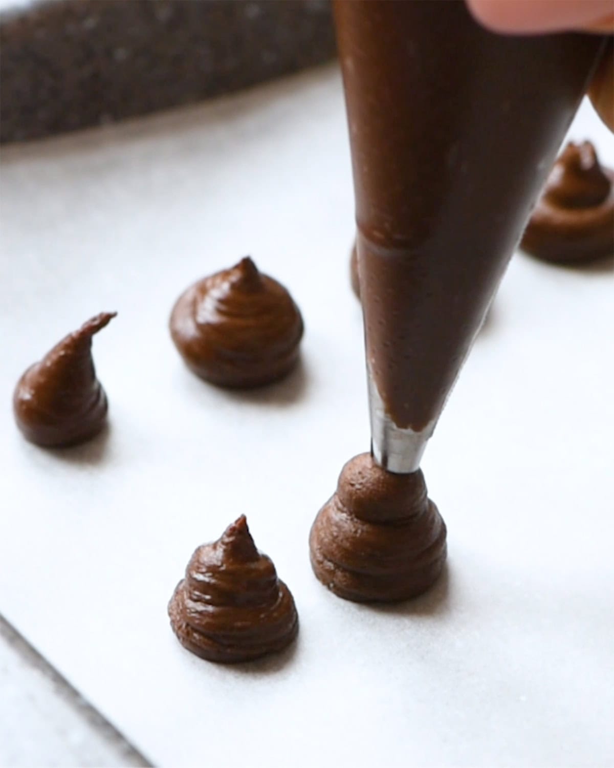 how to make almond butter blossoms - piping chocolate kisses onto a baking sheet