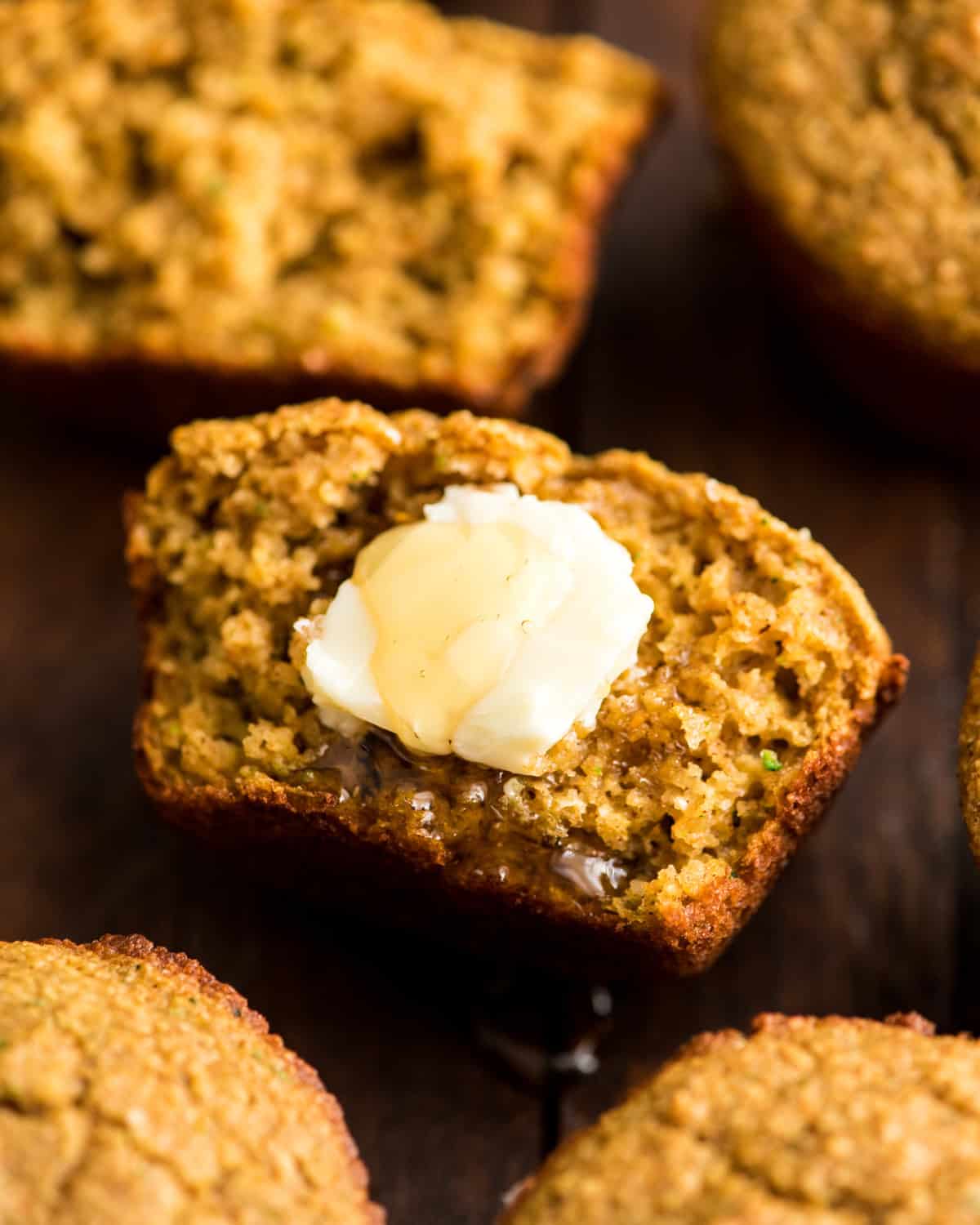 up close photo of half of a Carrot Zucchini Muffin with butter and honey
