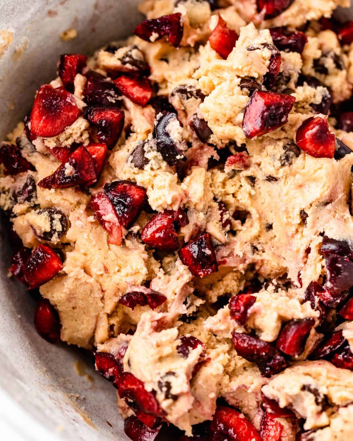 close up photo of the finished chocolate chip cherry cookies dough in a ceramic mixing bowl