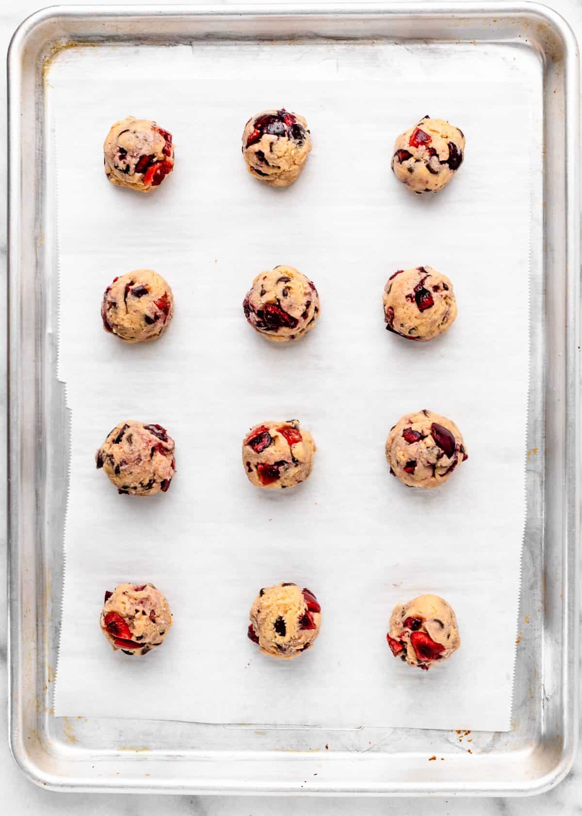 12 chocolate chip cherry cookies on a metal baking sheet lined with parchment paper before baking