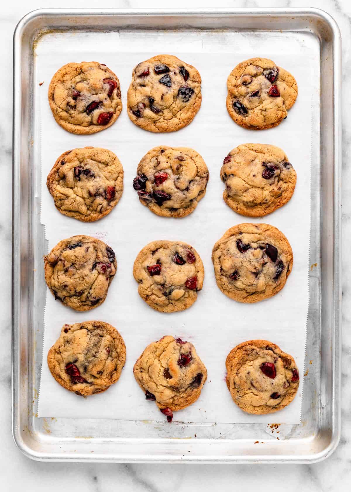 12 chocolate chip cherry cookies on a metal baking sheet lined with parchment paper after baking
