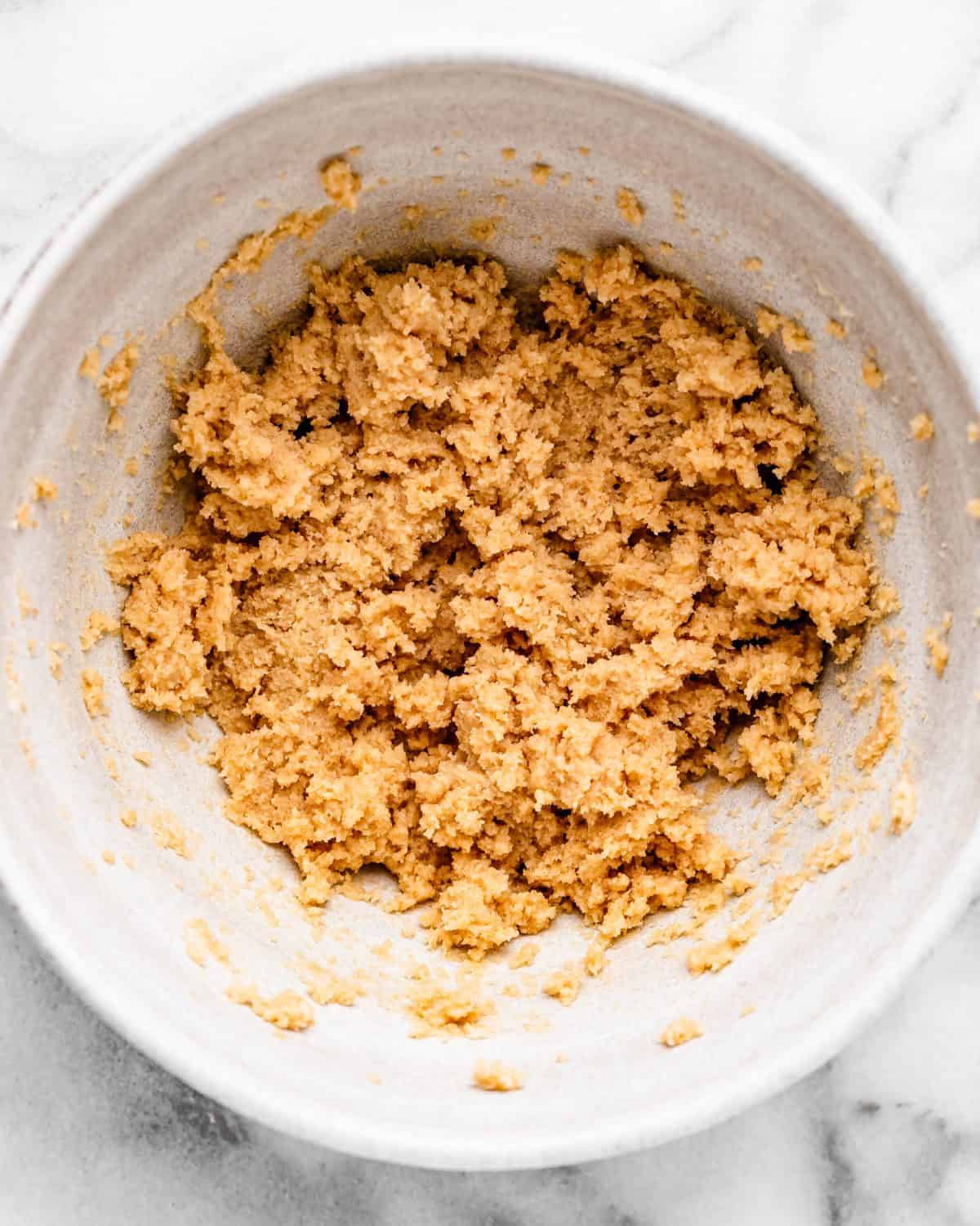 making cherry cookies - butter, white sugar and brown sugar in a ceramic mixing bowl beaten together