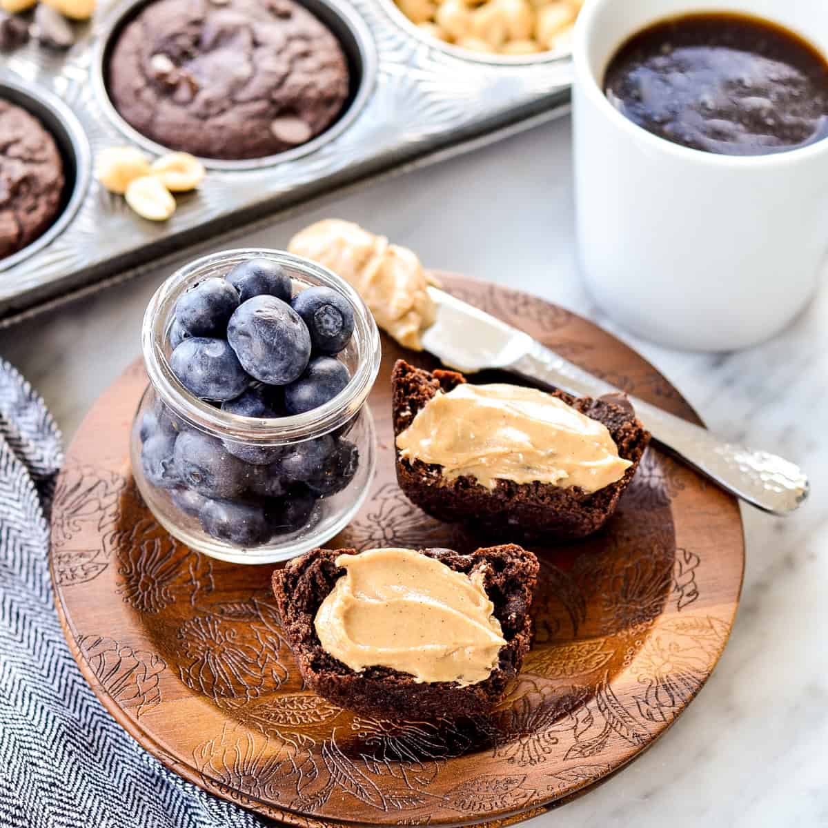 a Chocolate Peanut Butter Zucchini Muffins cut in half on a plate with peanut butter spread on it