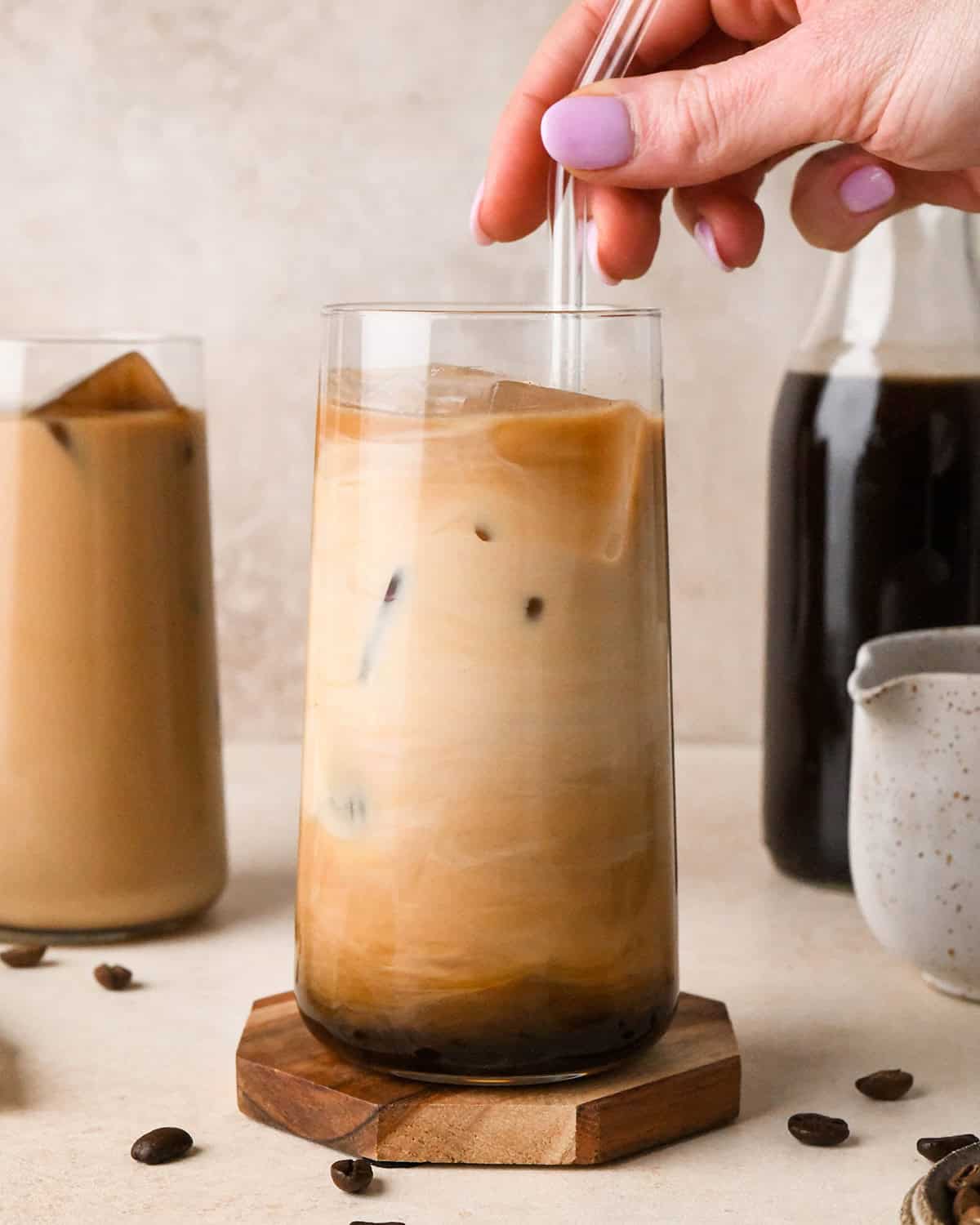 a hand stirring a glass of Cold Brew Coffee with a straw