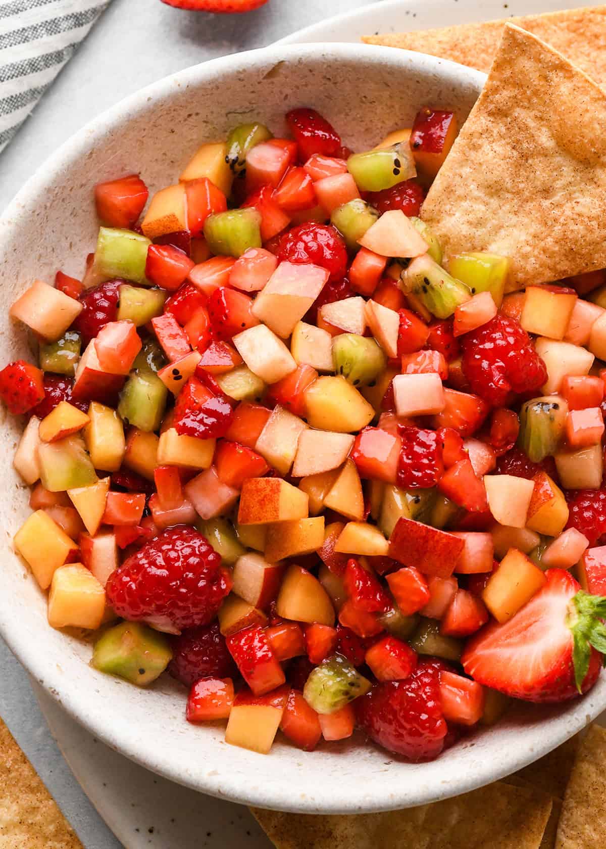 a bowl of fruit salsa with a cinnamon chip at the top 