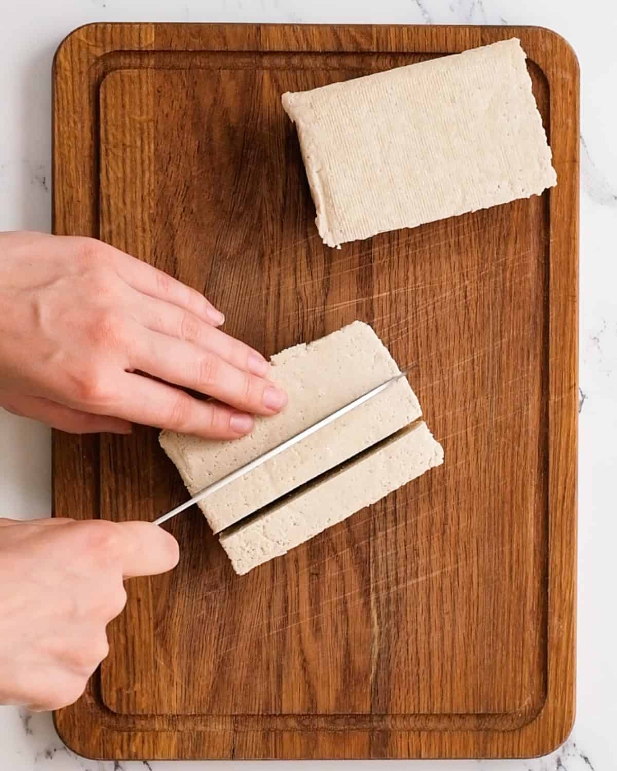 cutting tofu on a wooden cutting board