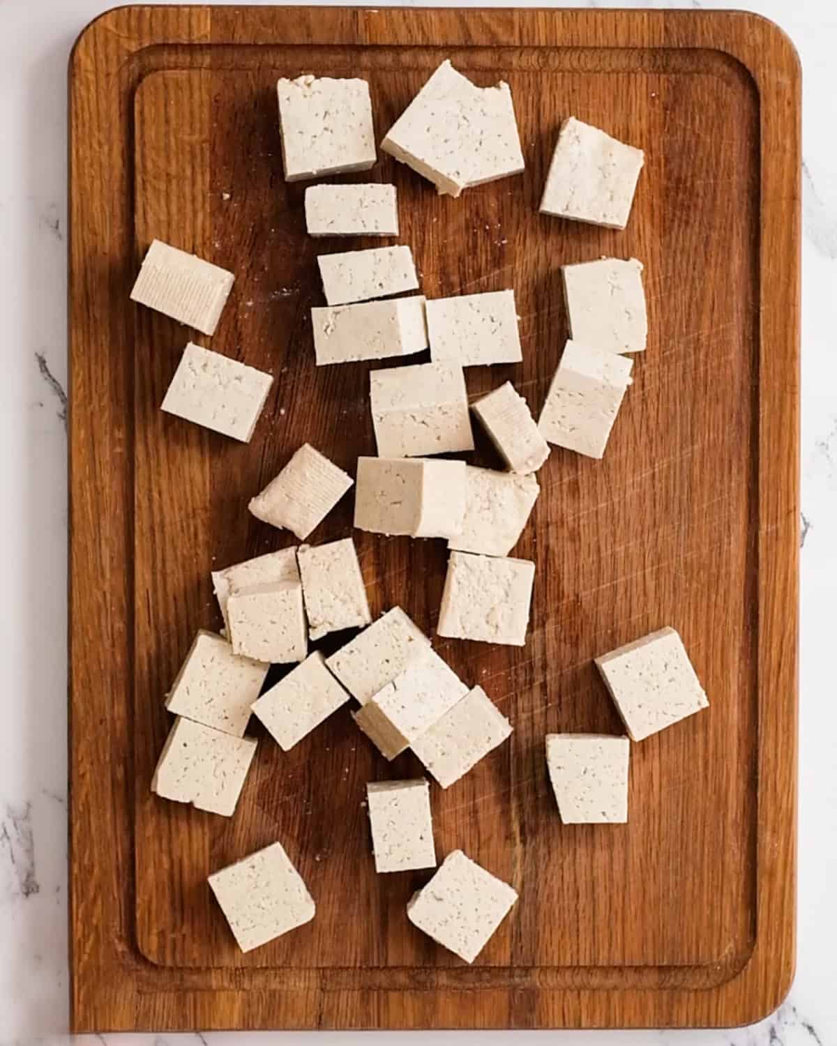 tofu cut into cubes on a wooden cutting board