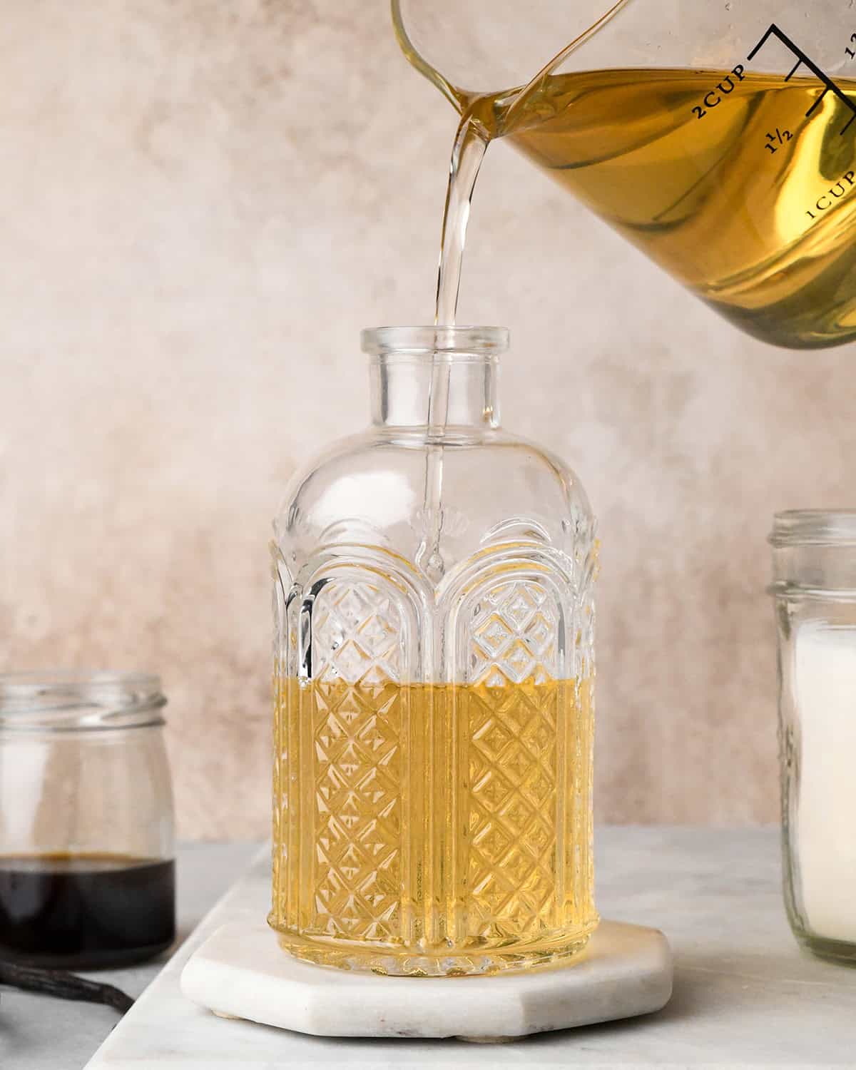 pouring simple syrup into a glass jar