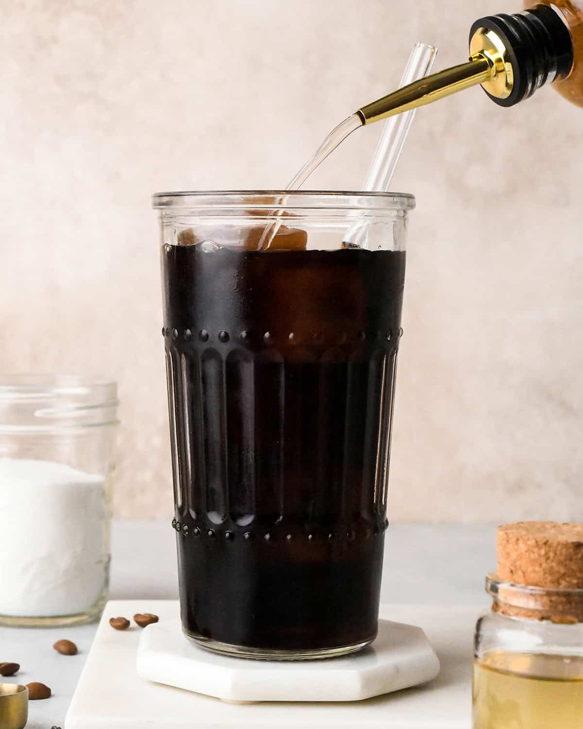 Simple Syrup being poured into a cup of iced coffee