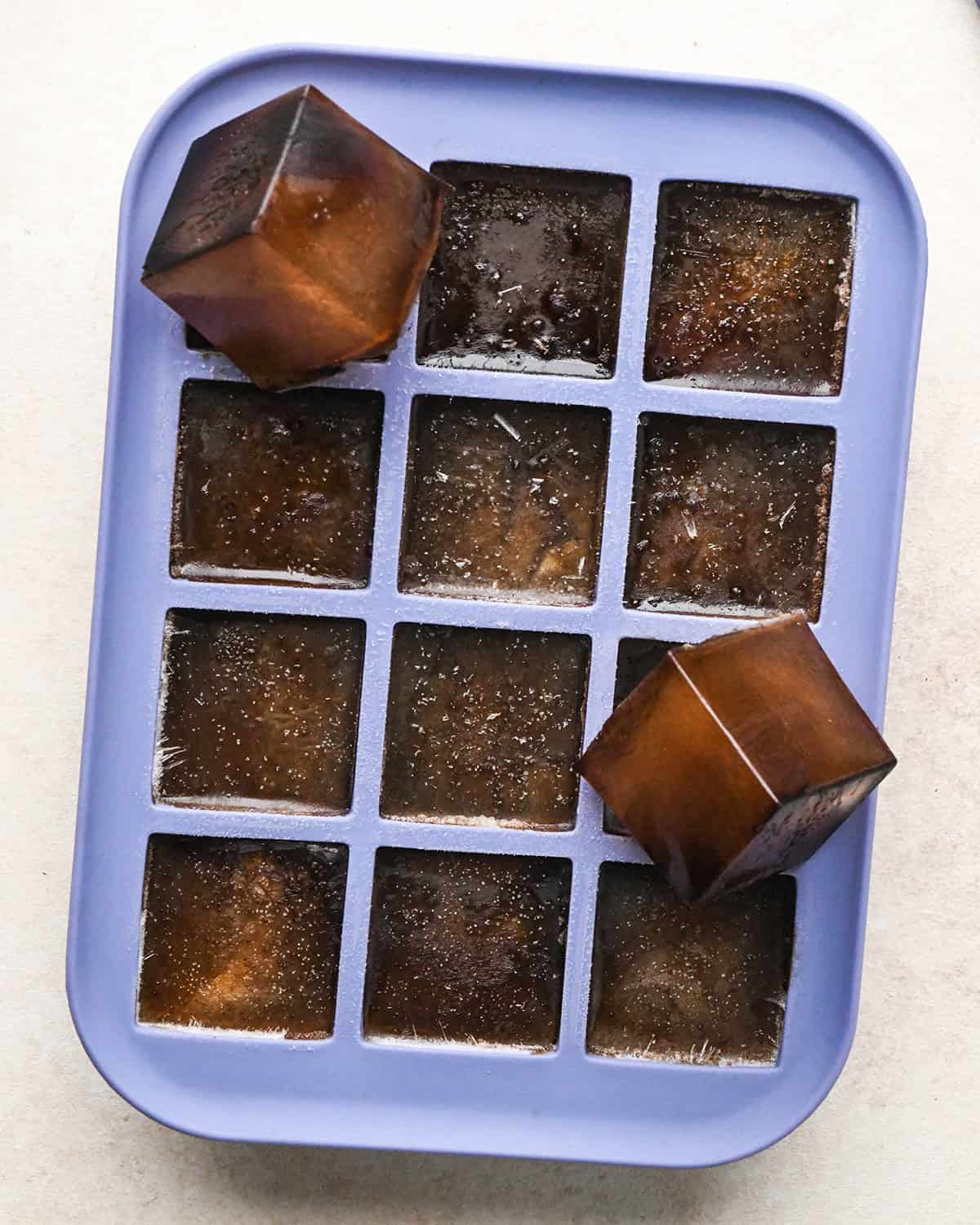 Coffee Ice Cubes in an ice cube tray - two have been removed from the tray and are resting on it