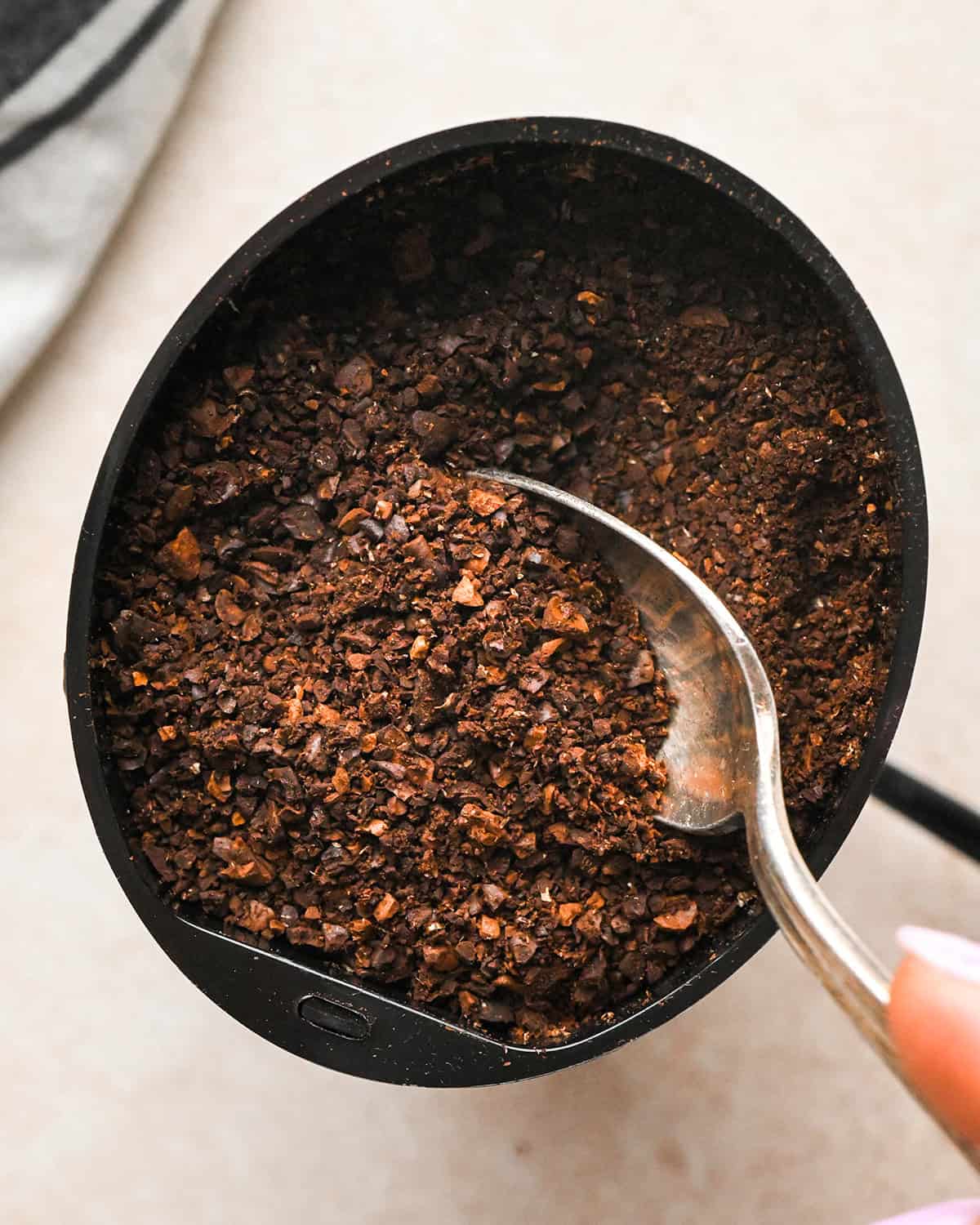 coarsely ground coffee in a grinder with a spoon to make cold brew coffee