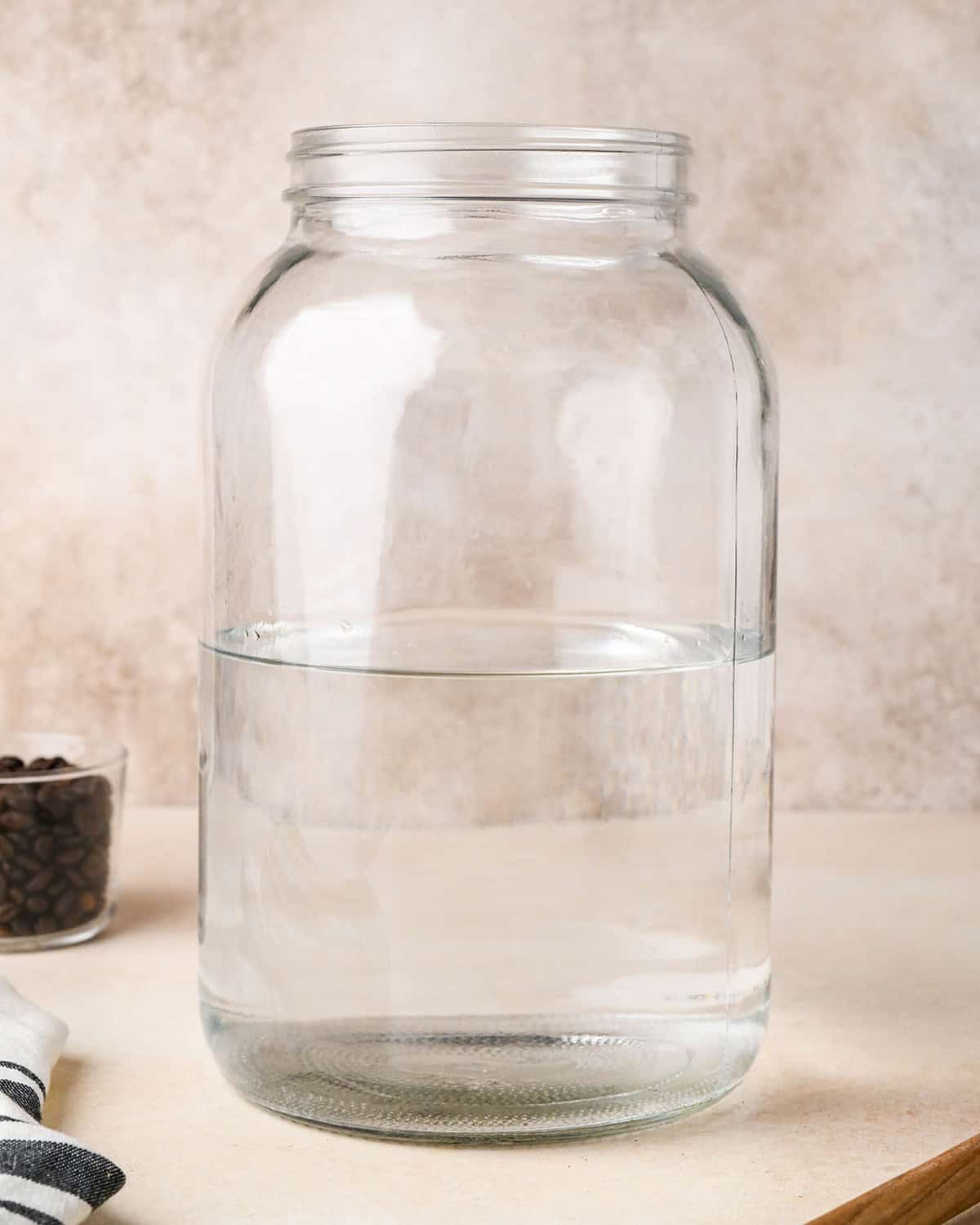 How to Make Cold Brew Coffee Recipe - a glass, 1 gallon jar half filled with water. 
