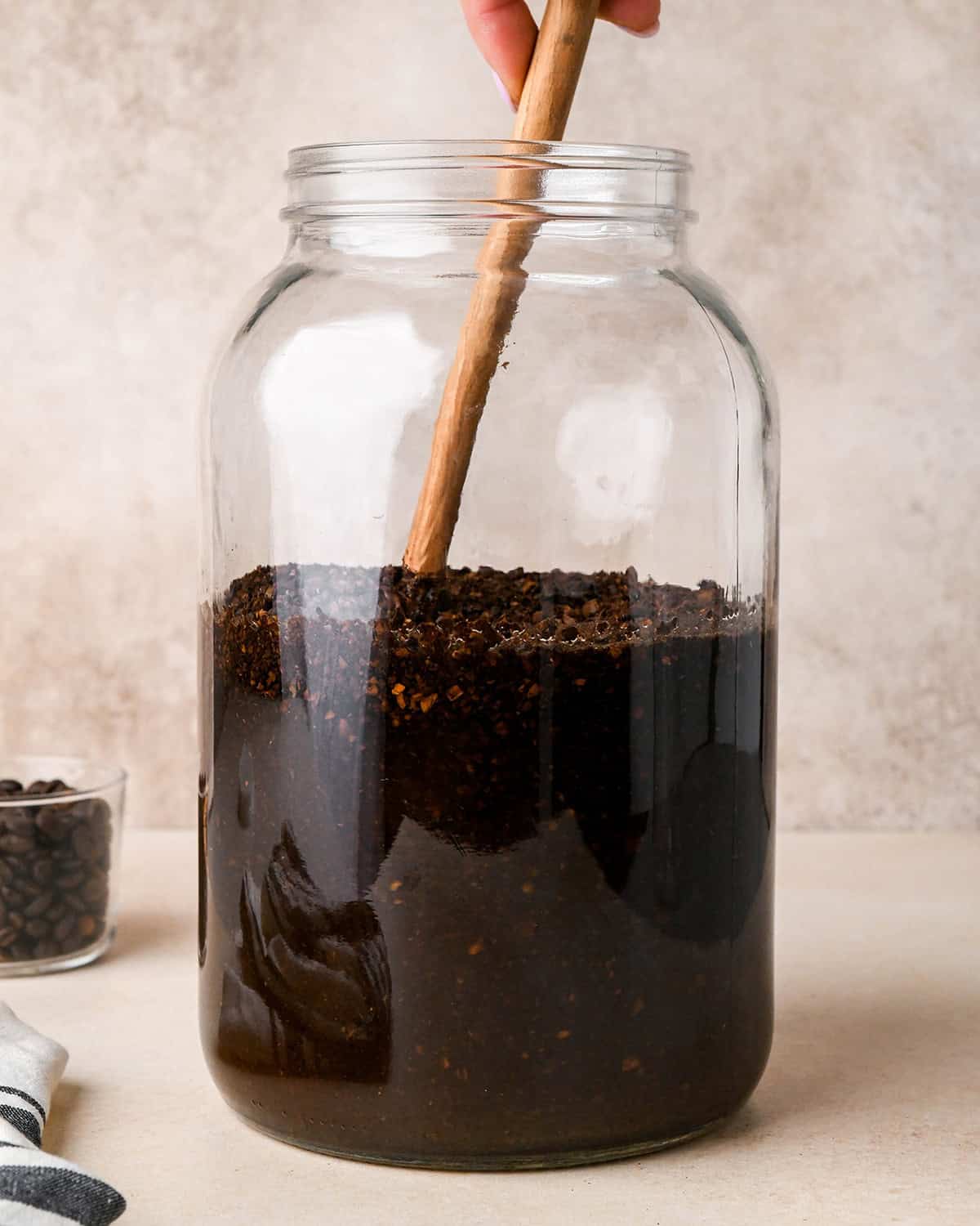 How to Make Cold Brew Coffee Recipe - a wooden spoon stirring the coffee grounds into the water in the glass jar. 