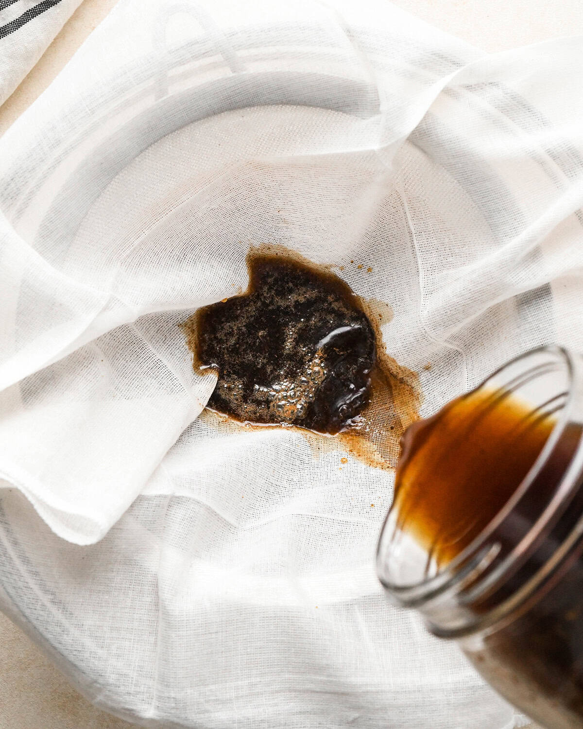 How to Make Cold Brew Coffee Recipe - straining coffee grounds through a cheesecloth and fine mesh strainer