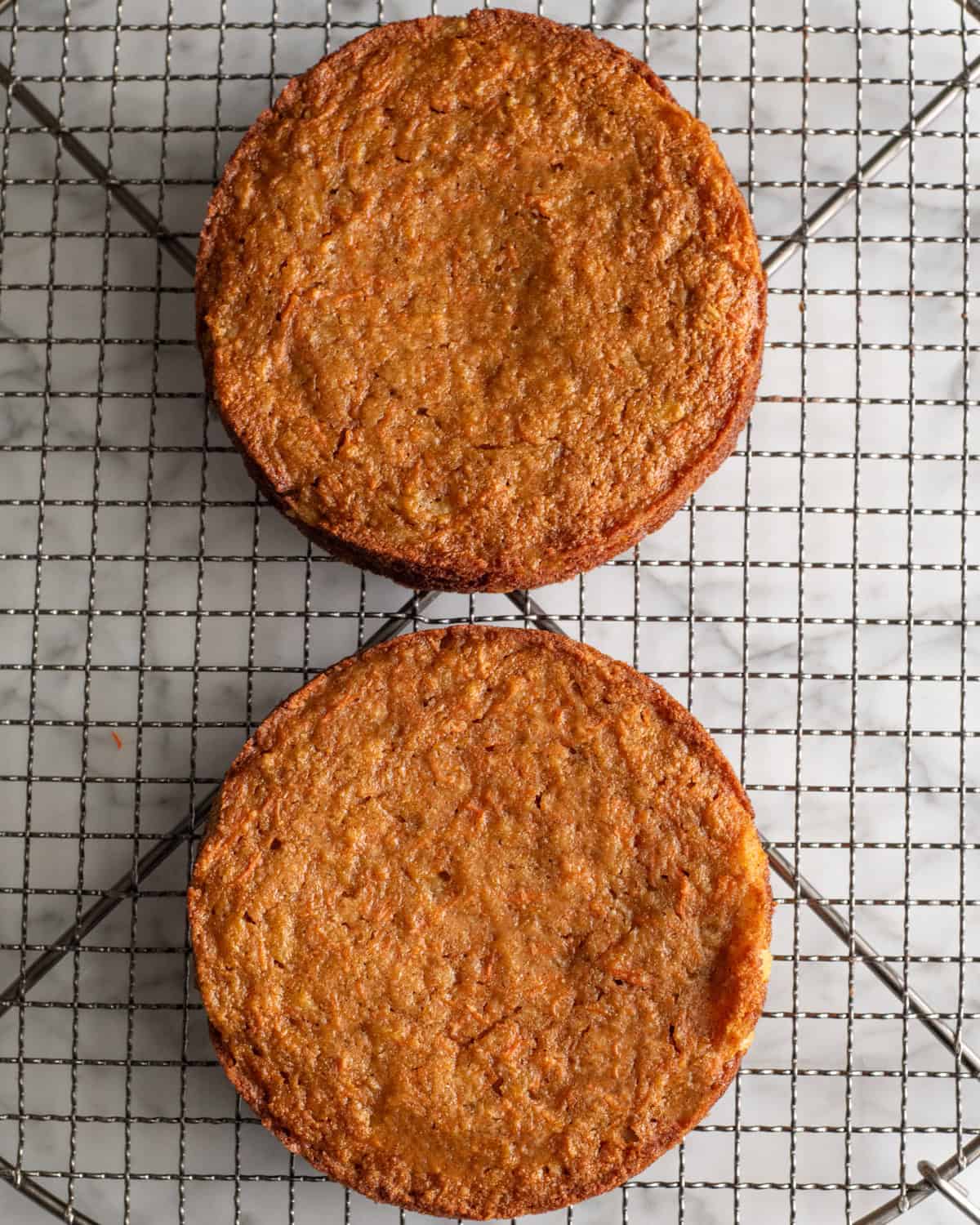 two Gluten-Free Carrot Cake rounds on a wire cooling rack after baking