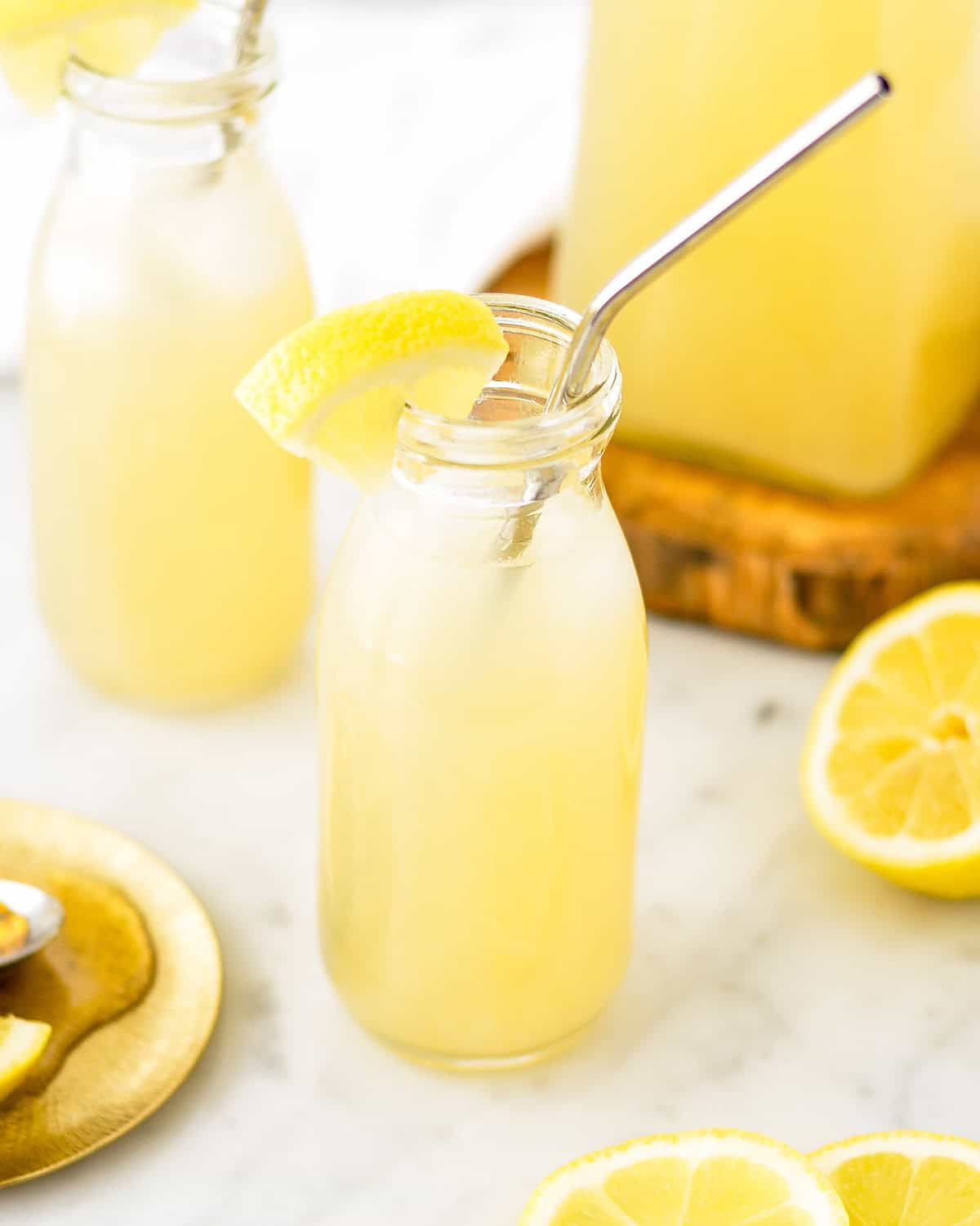 Orange Blossom Lemonade in a glass with a metal straw and a lemon wedge