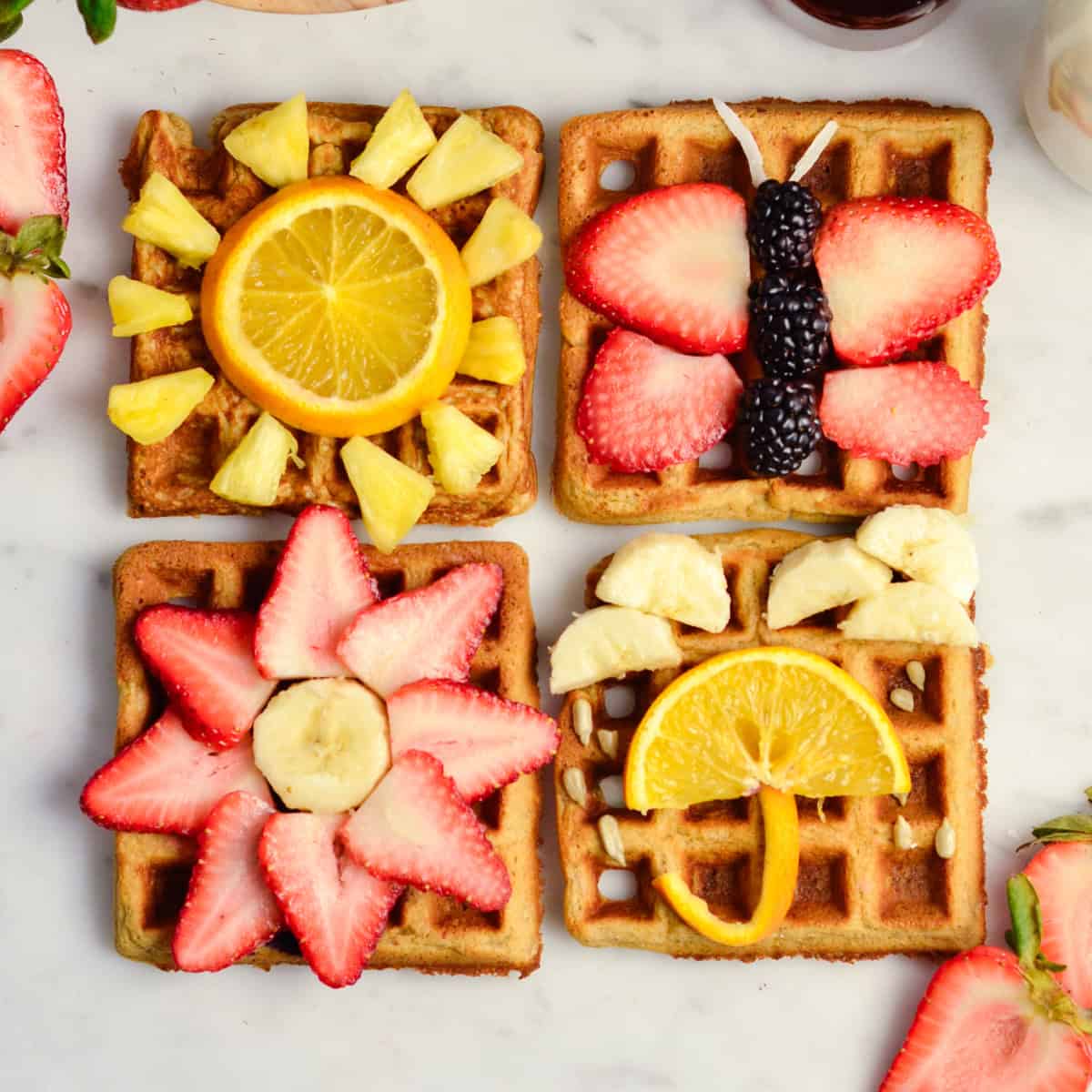 4 Peanut Butter Banana Oatmeal Waffles with cute scenes on them made out of fruit