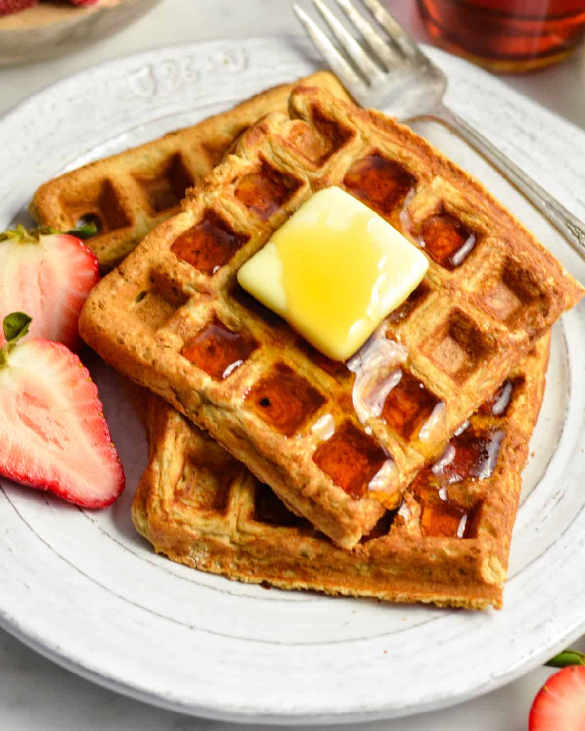 3 Peanut Butter Banana Oatmeal Waffles on a plate with butter and syrup 