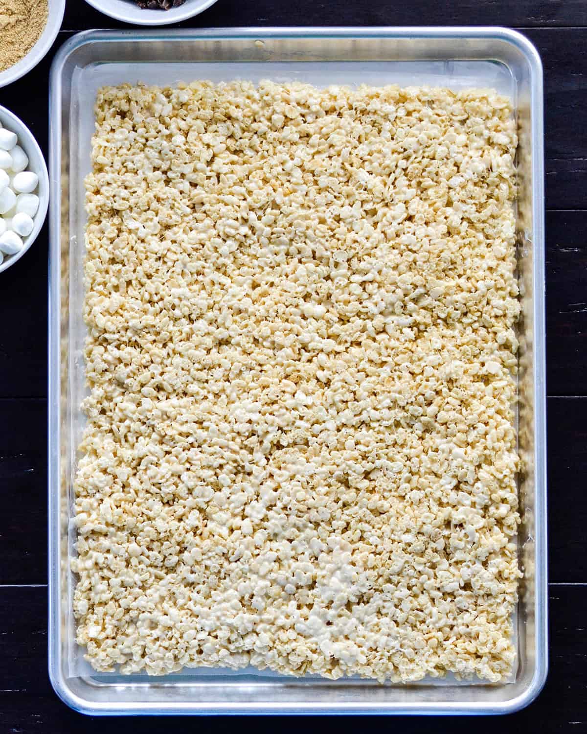 how to make Rice Crispy Dessert Sushi - rice crispy mixture pressed into a rectangle on a baking sheet