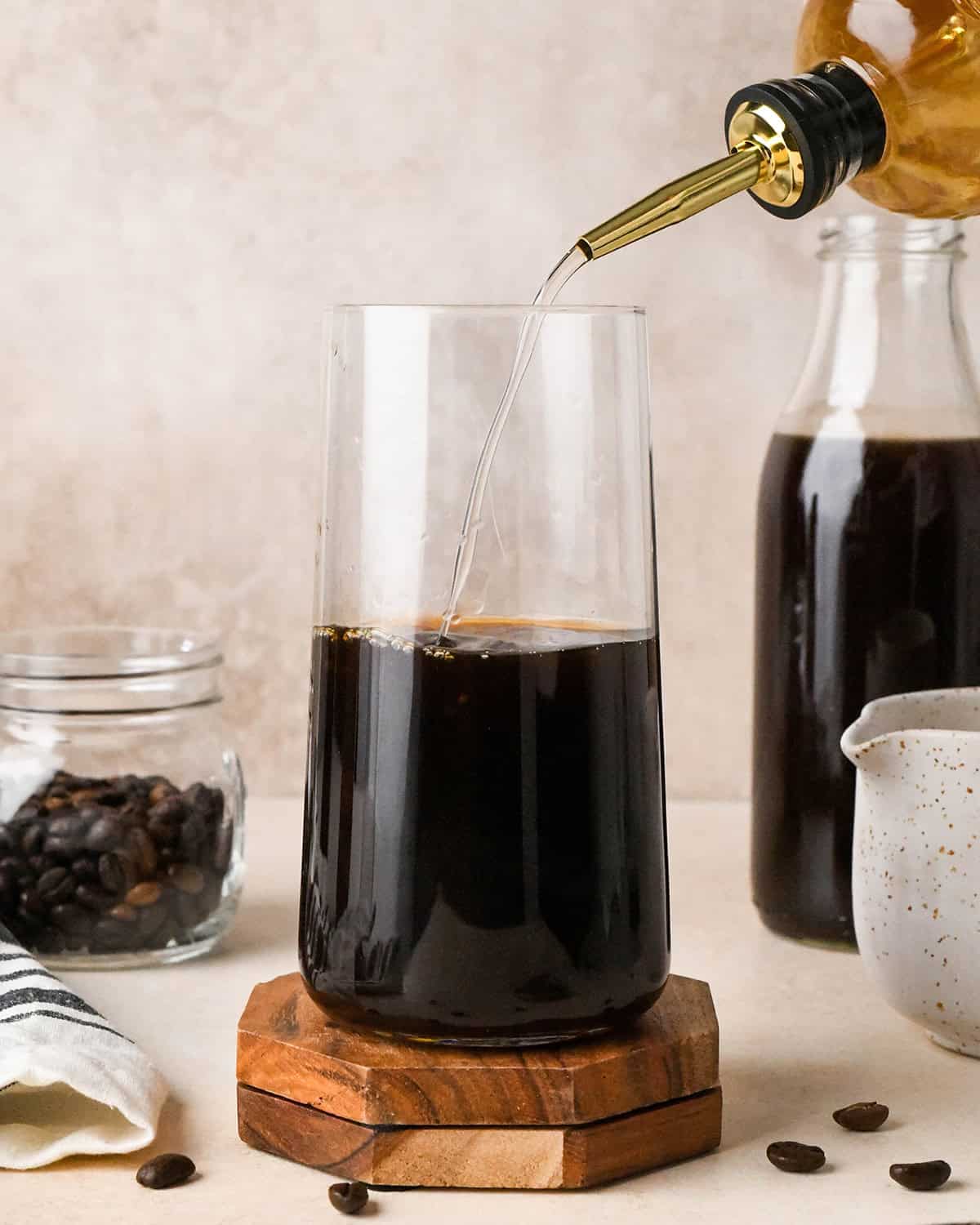 Simple Syrup being poured into a cup of iced coffee