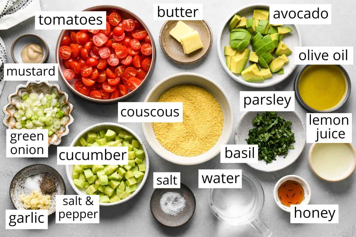 overhead photo of the labeled ingredients in this Couscous Salad recipe like couscous, tomatoes, avocado, cucumber, green onion, olive oil, herbs and more