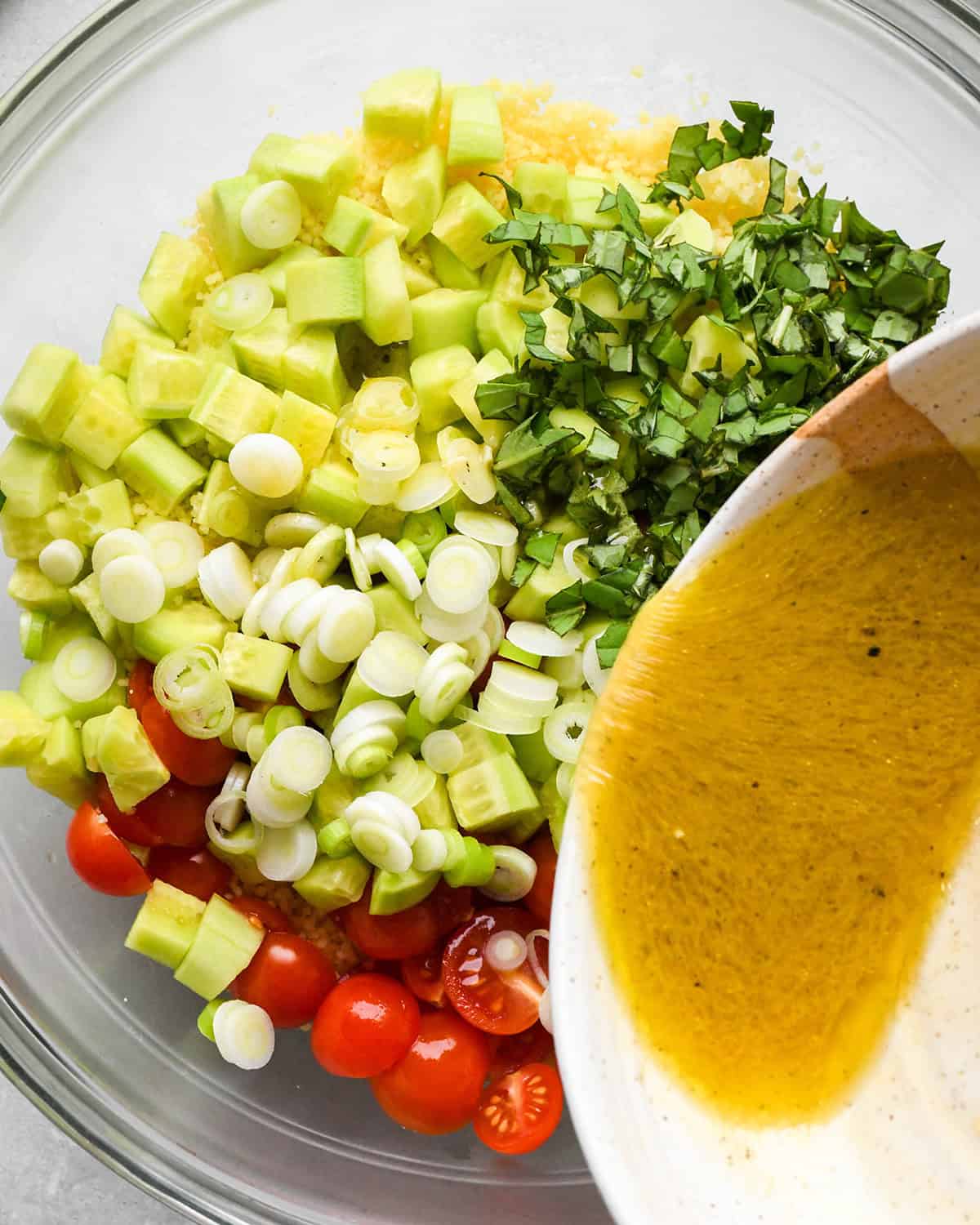 assembling Couscous Salad - dressing being poured over ingredients in a bowl
