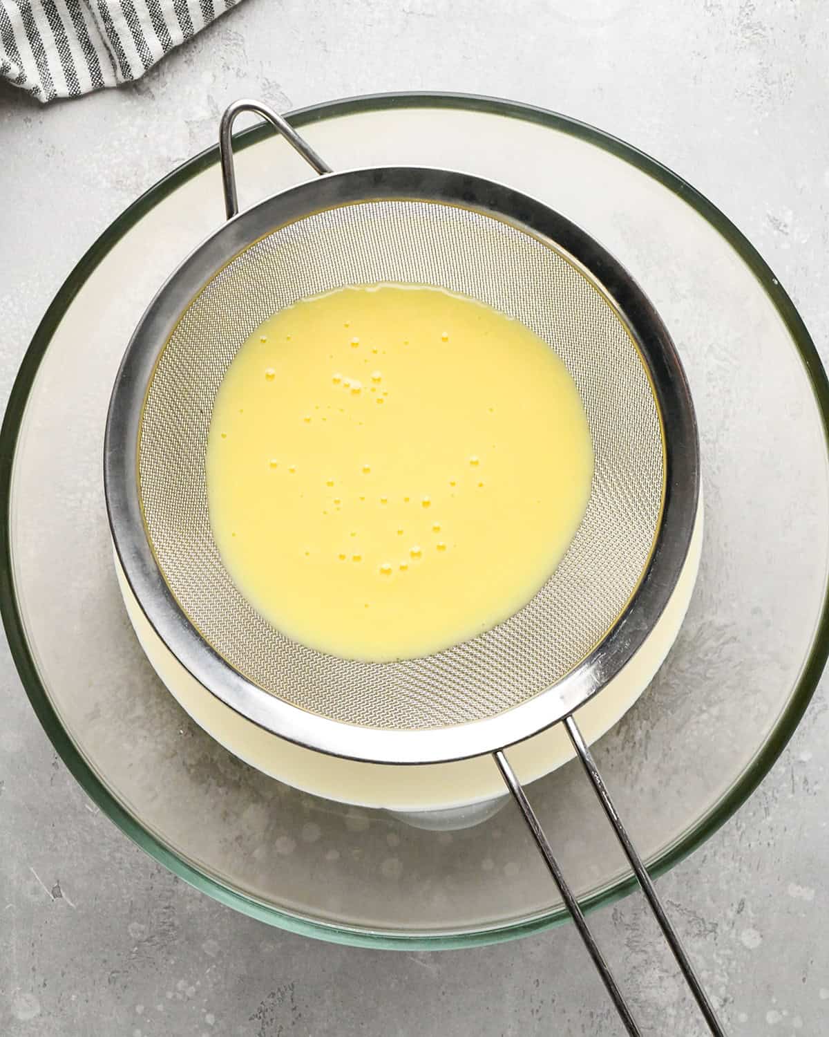 making Mint Chocolate Chip Ice Cream - custard poured into the metal strainer over cream in a bowl