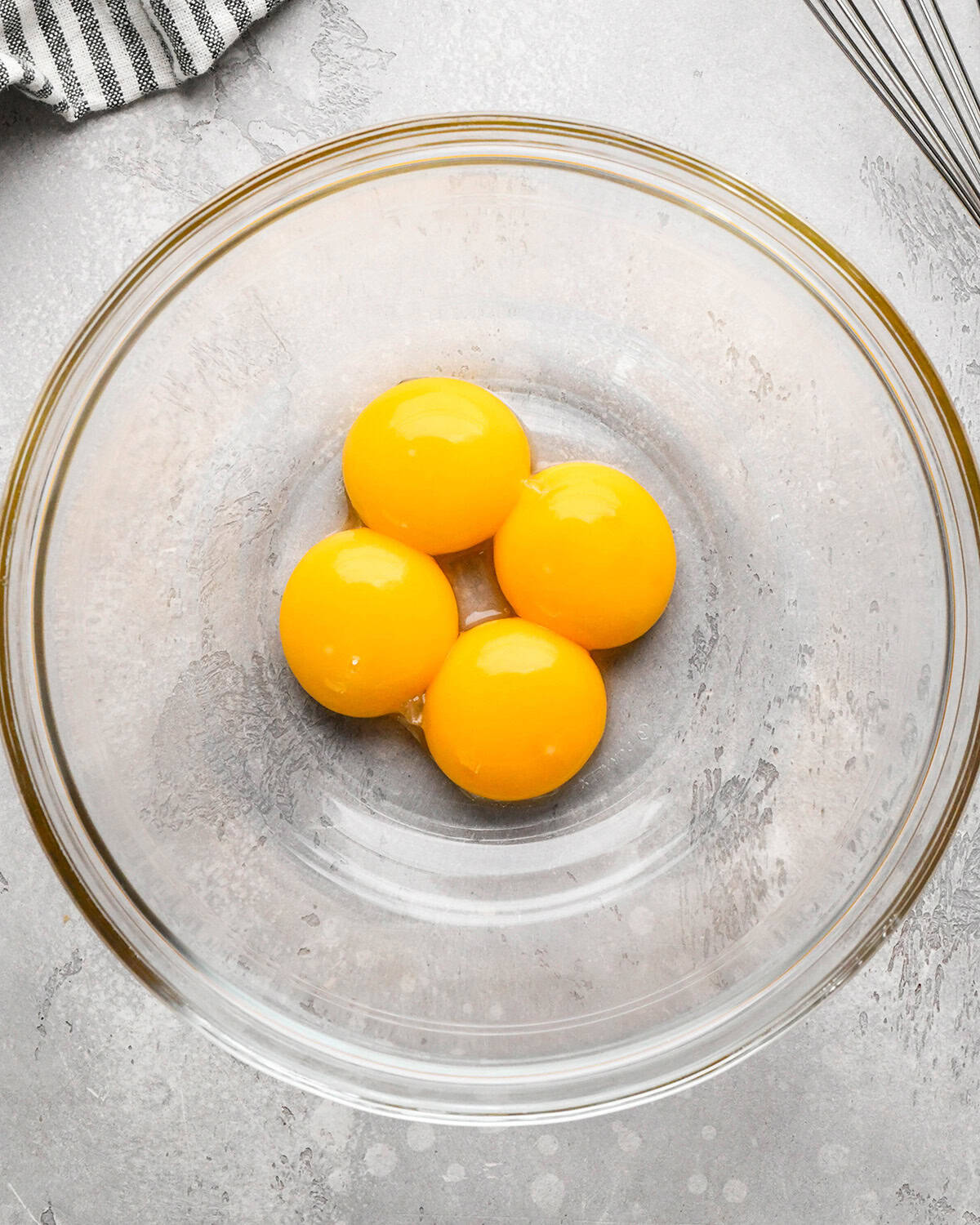 4 egg yolks in a glass bowl before whisking