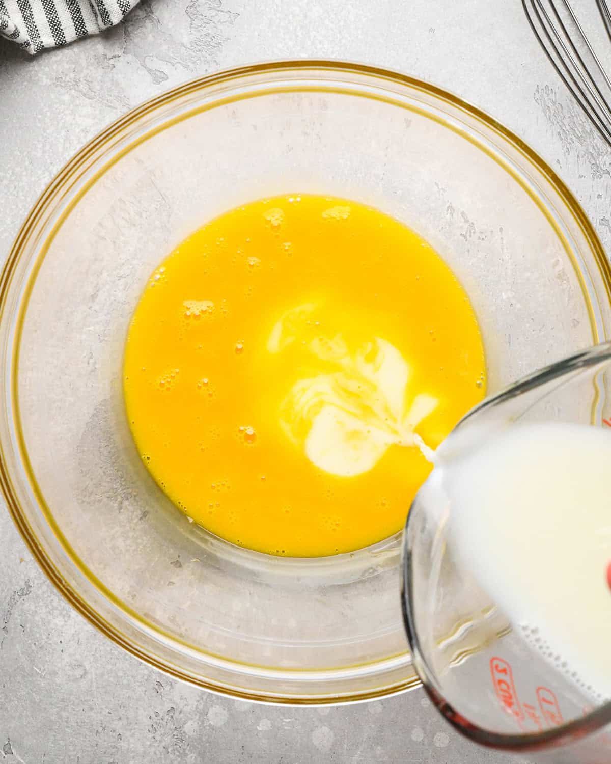 making Mint Chocolate Chip Ice Cream - warm milk being poured into whisked egg yolks
