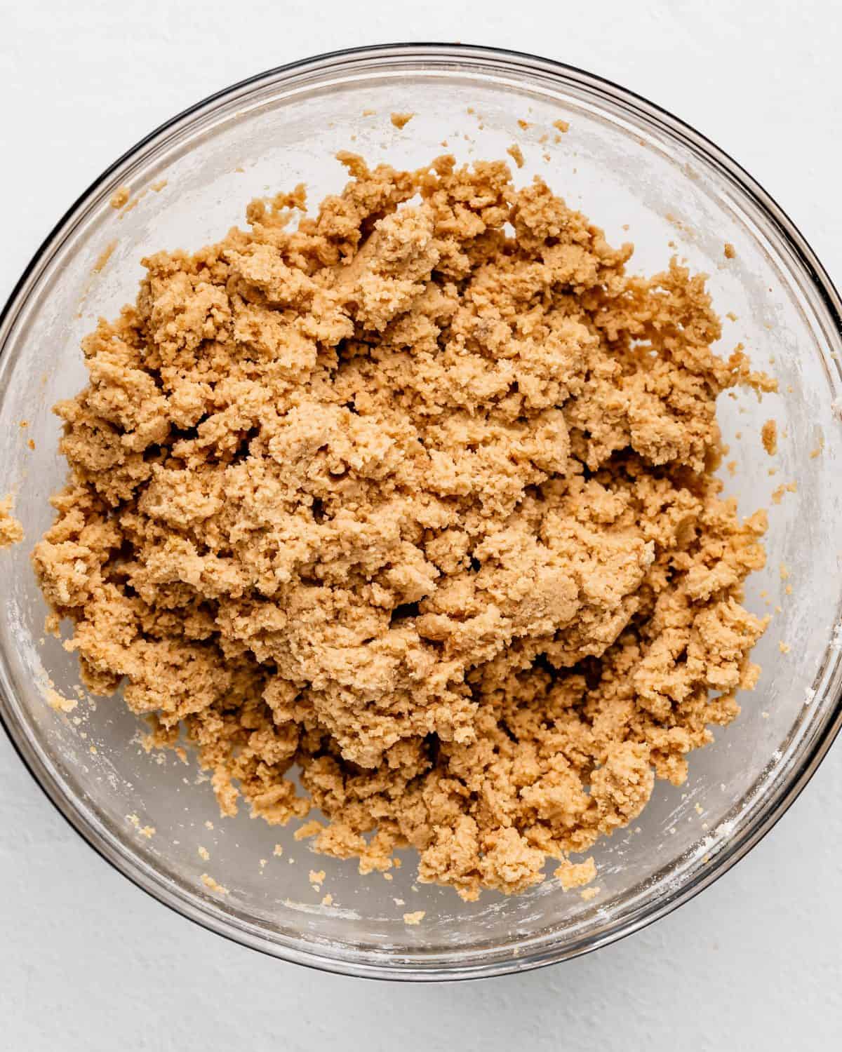making s'mores cookies recipe - cookie dough mixed together in a glass bowl on a white surface